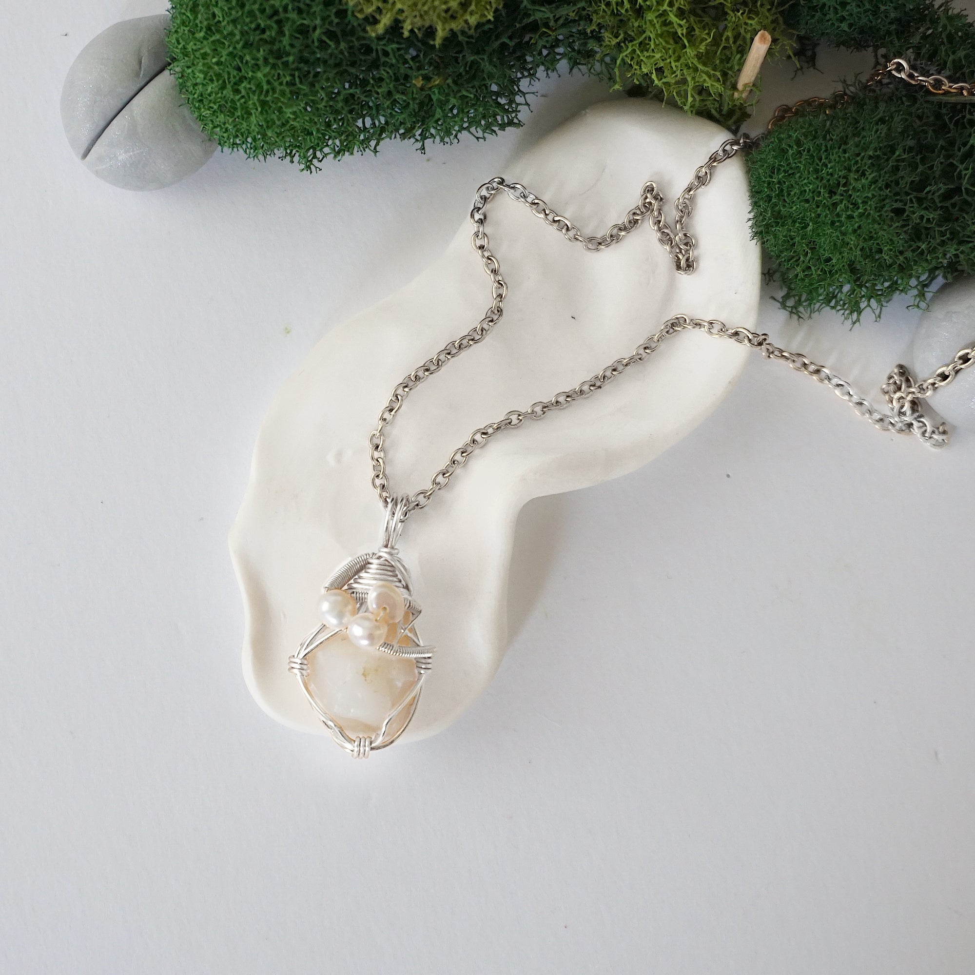 Handmade silver wire wrapped opal and freshwater pearl necklace laying flat on a silver plated chain, artisan jewelry for women