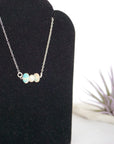 Focused left-side close-up of sterling silver opal and pearl bar necklace on jewelry display