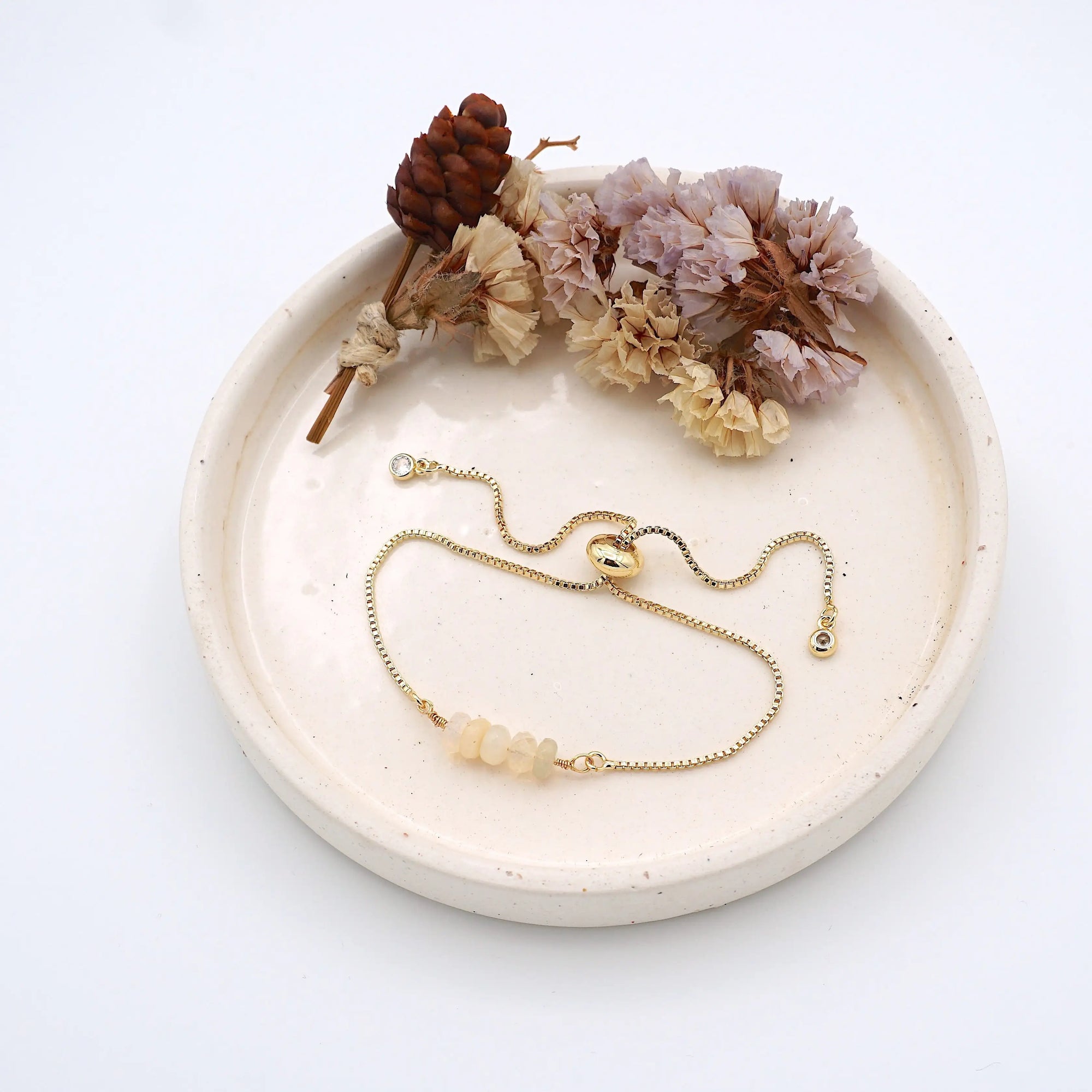 Handmade opal bracelet displayed on ceramic tray showing natural iridescent crystals and gold chain - October birthstone gift for her