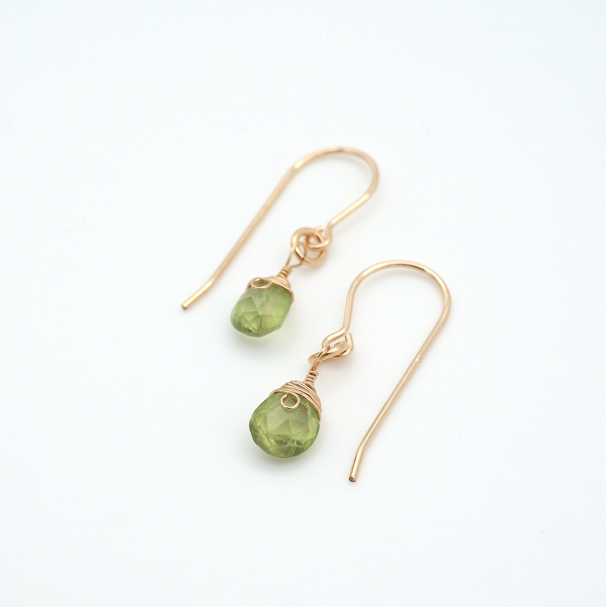 Angled look at peridot drop earrings, artisan wire wrapping in 14k gold filled, August birthstone