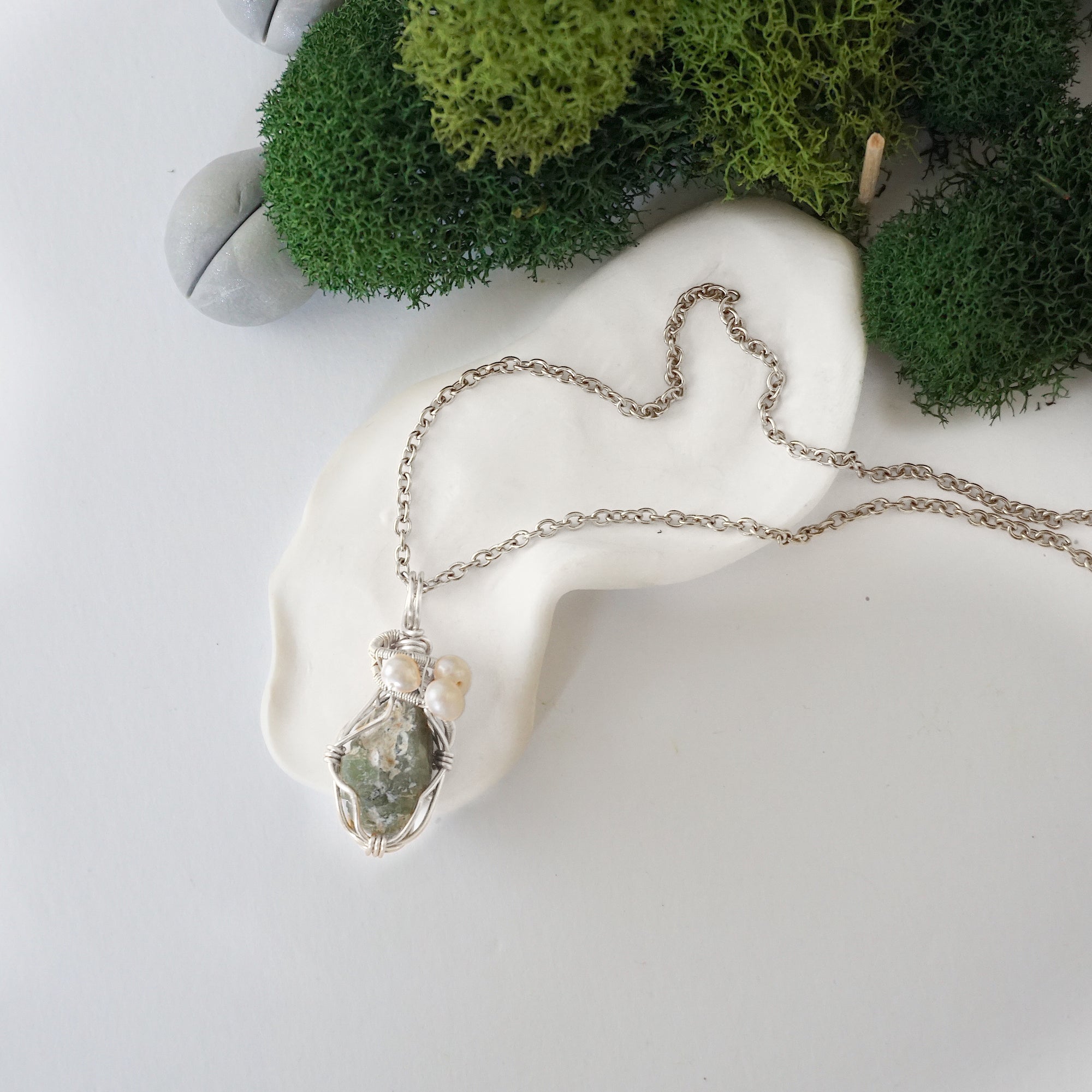 Handmade silver wire wrapped peridot and freshwater pearl necklace laying flat on a silver plated chain, artisan jewelry for women