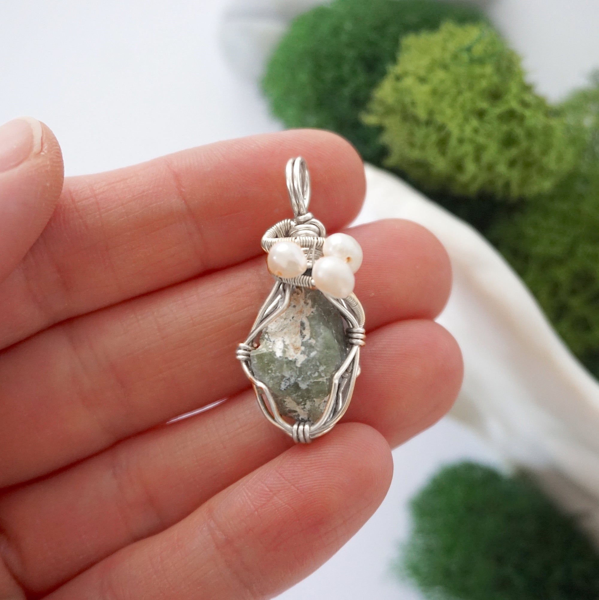 Peridot and freshwater pearl pendant necklace in hand for size reference, silver wire wrapped, handcrafted gemstone jewelry