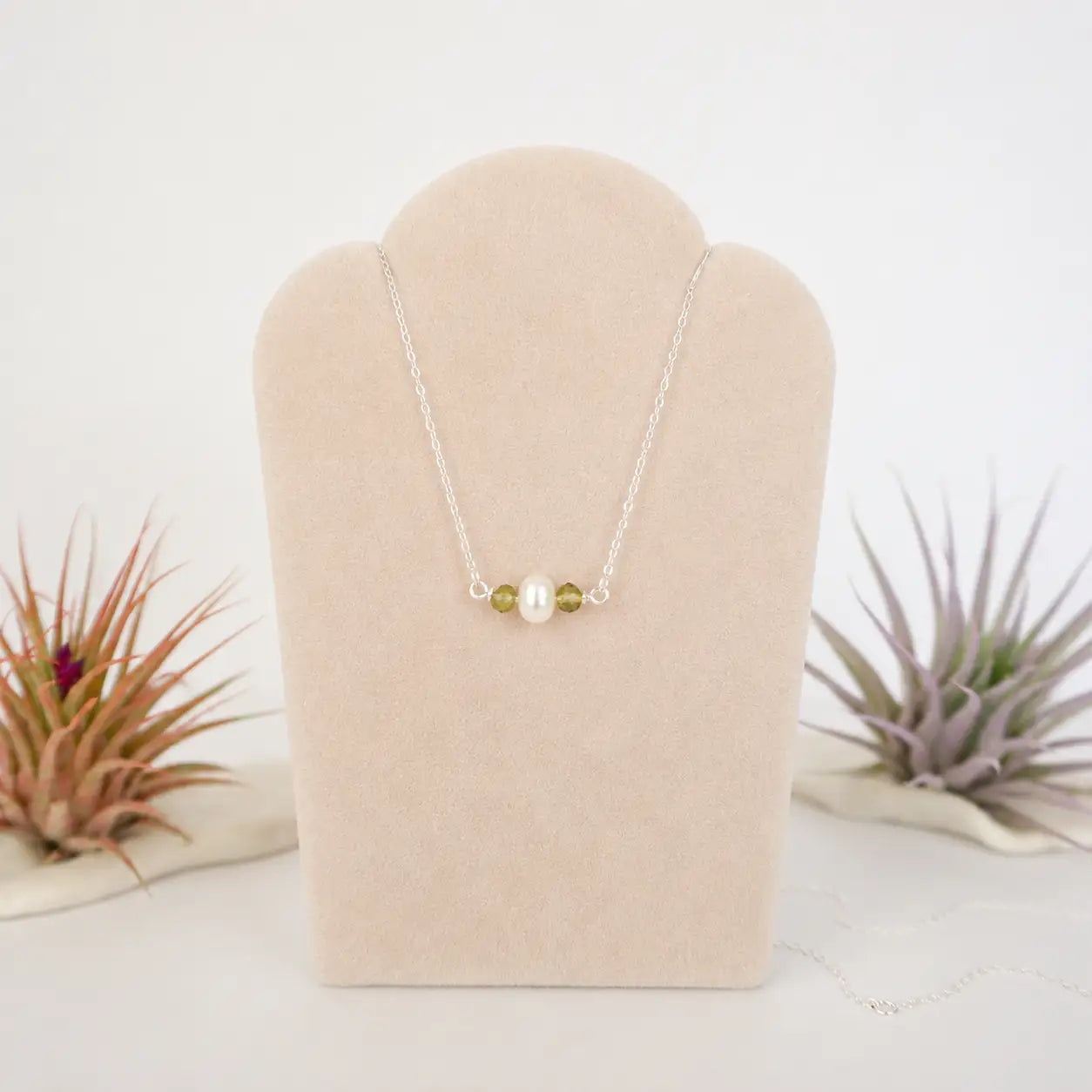 Peridot and freshwater pearl bar necklace in 925 sterling silver on jewelry display, front view