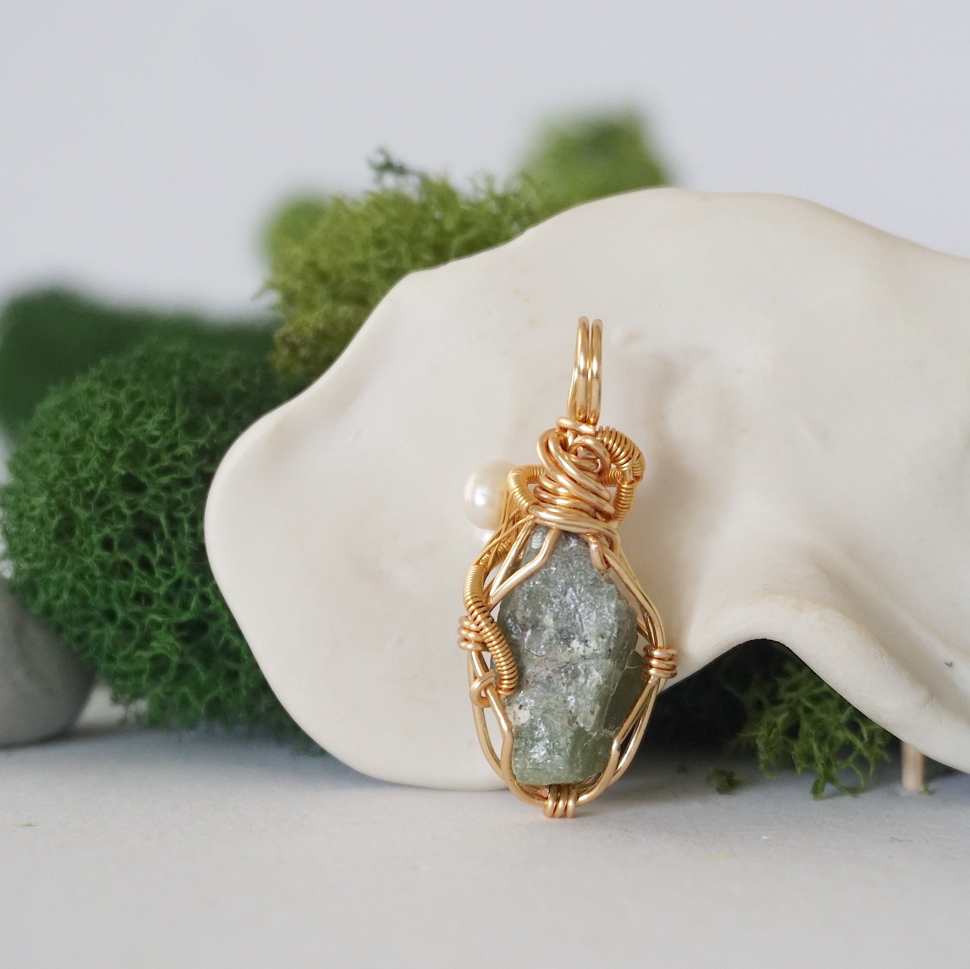 Back angle detail of peridot and freshwater pearl pendant, showing wire wrapping and natural stone