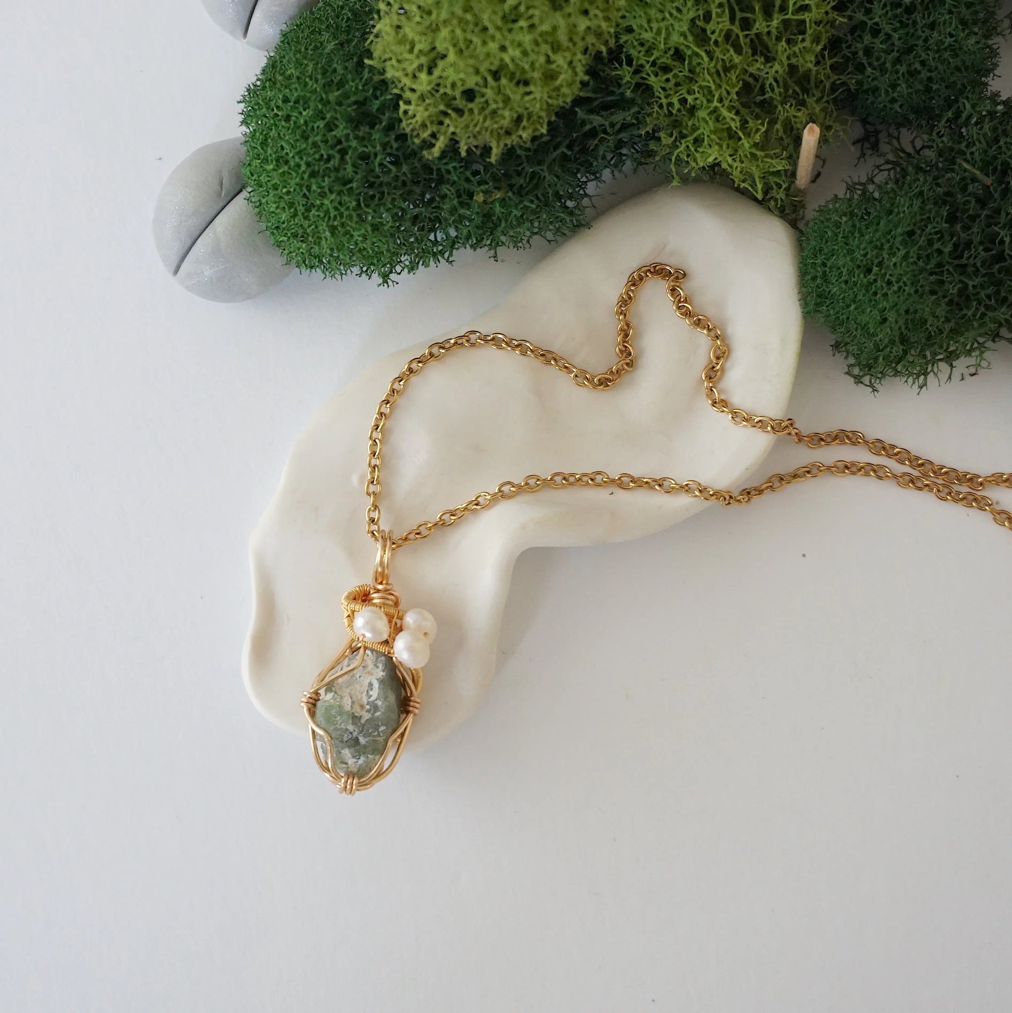 Peridot and freshwater pearl pendant on gold plated brass chain laying flat, handmade wire wrapped jewelry for women