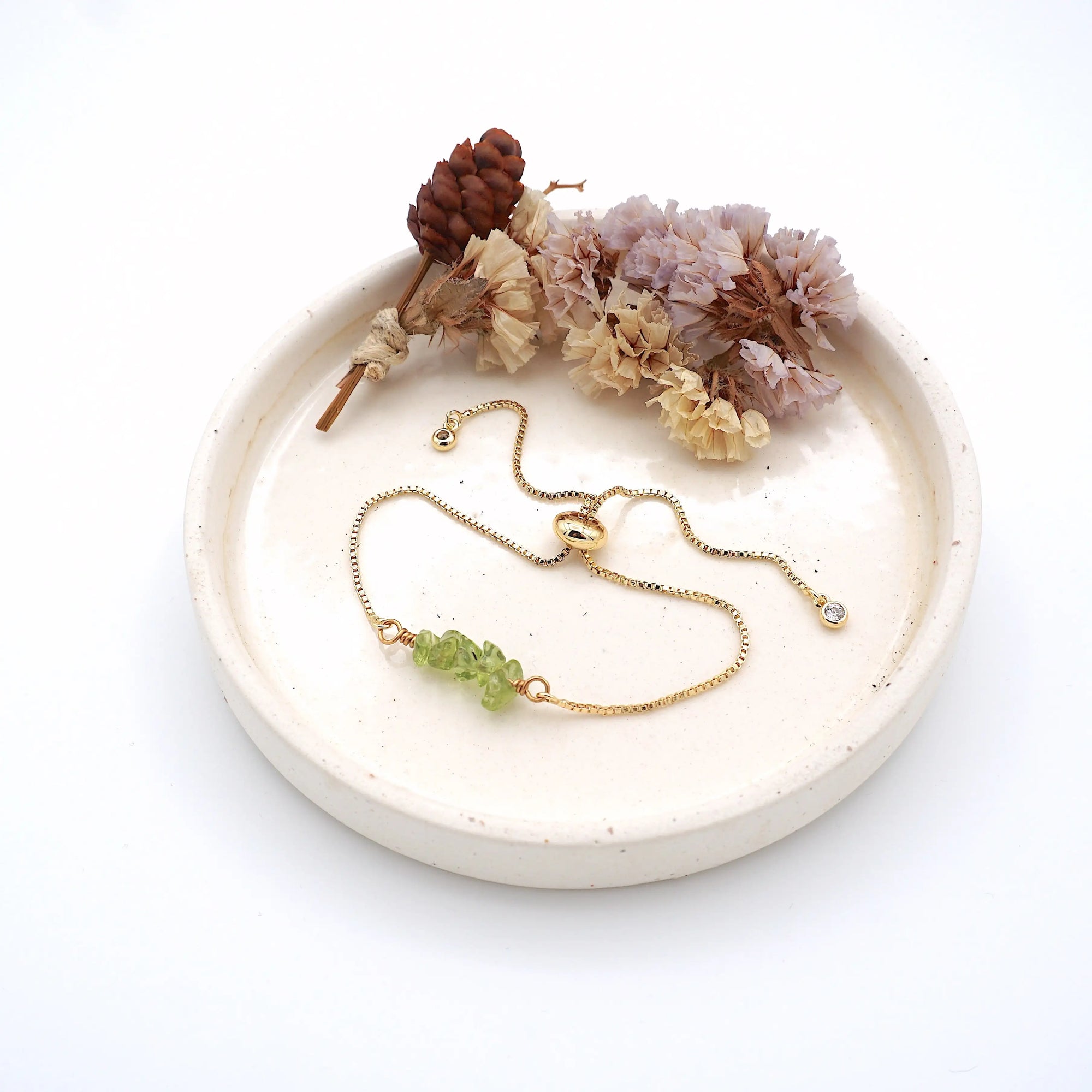 Peridot slider bracelet gold displayed on ceramic tray, adjustable August birthstone gift for women