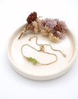 Peridot slider bracelet gold displayed on ceramic tray, adjustable August birthstone gift for women