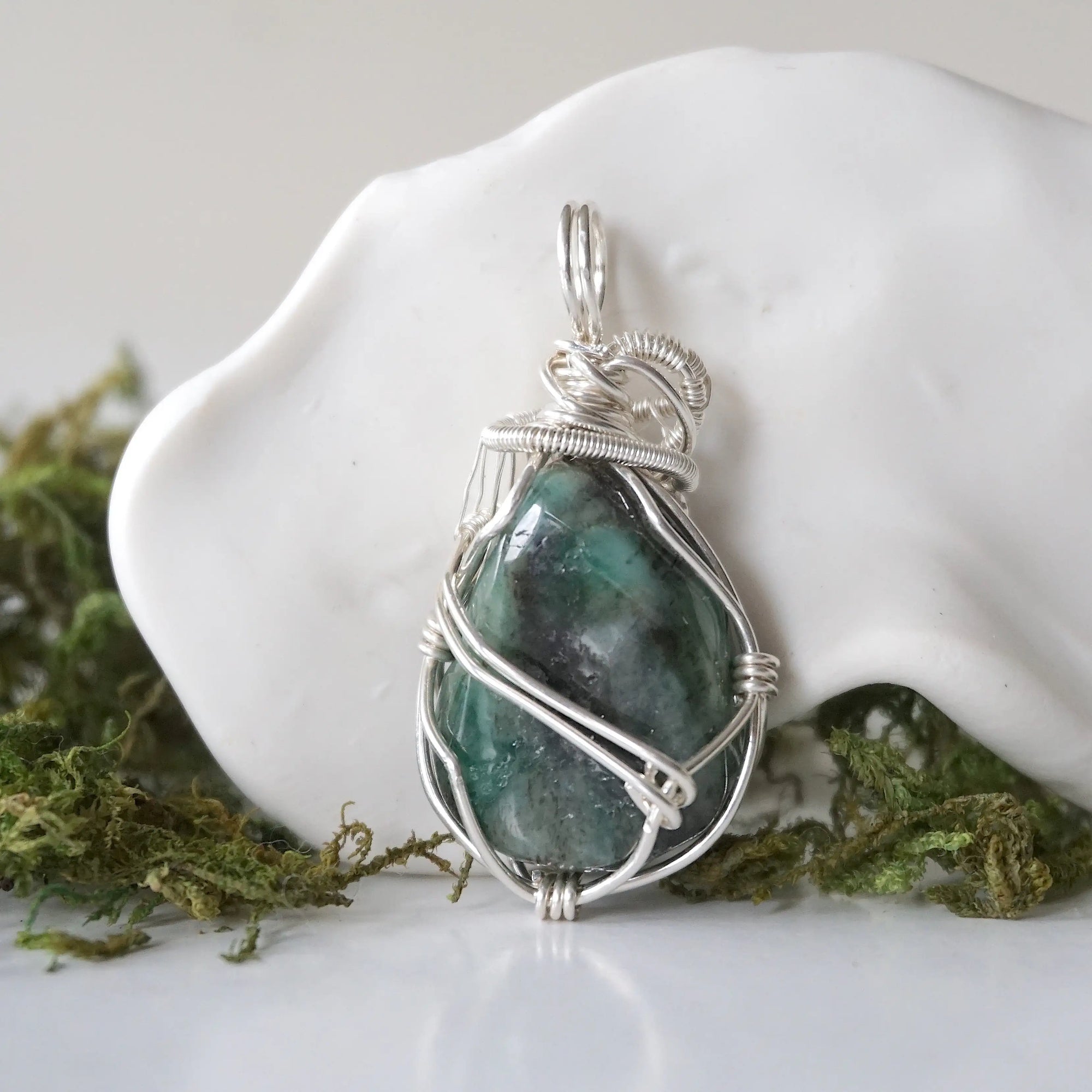 Back angle detail of polished raw emerald pendant necklace for women with natural emerald and handcrafted sterling silver wrapping