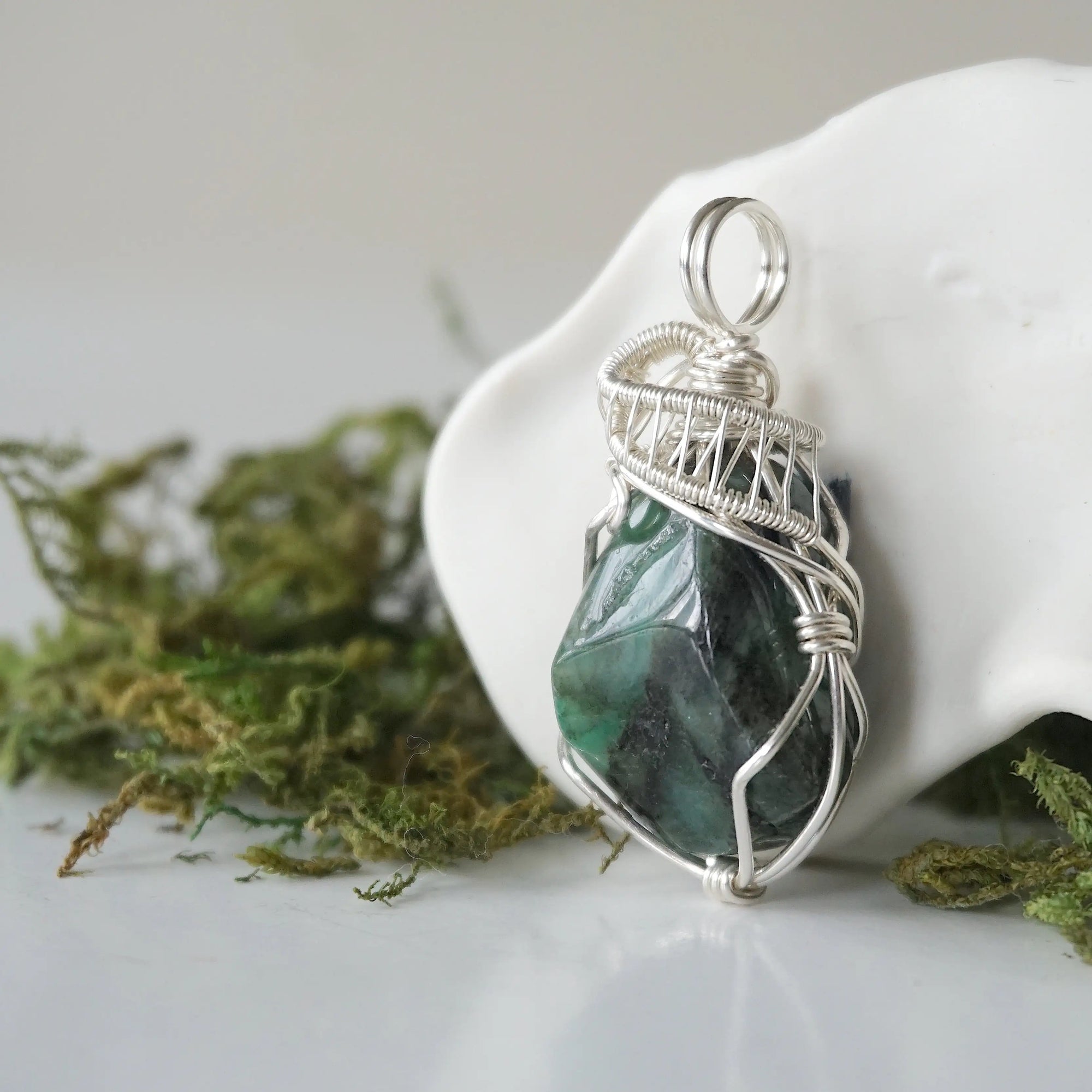 Left angle view of emerald necklace for women with natural polished-raw emerald and detailed sterling silver wire wrapping