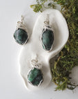 Three polished raw emerald pendants for women showing natural variation in emerald size, shape, and green colour in sterling silver wire wrapping
