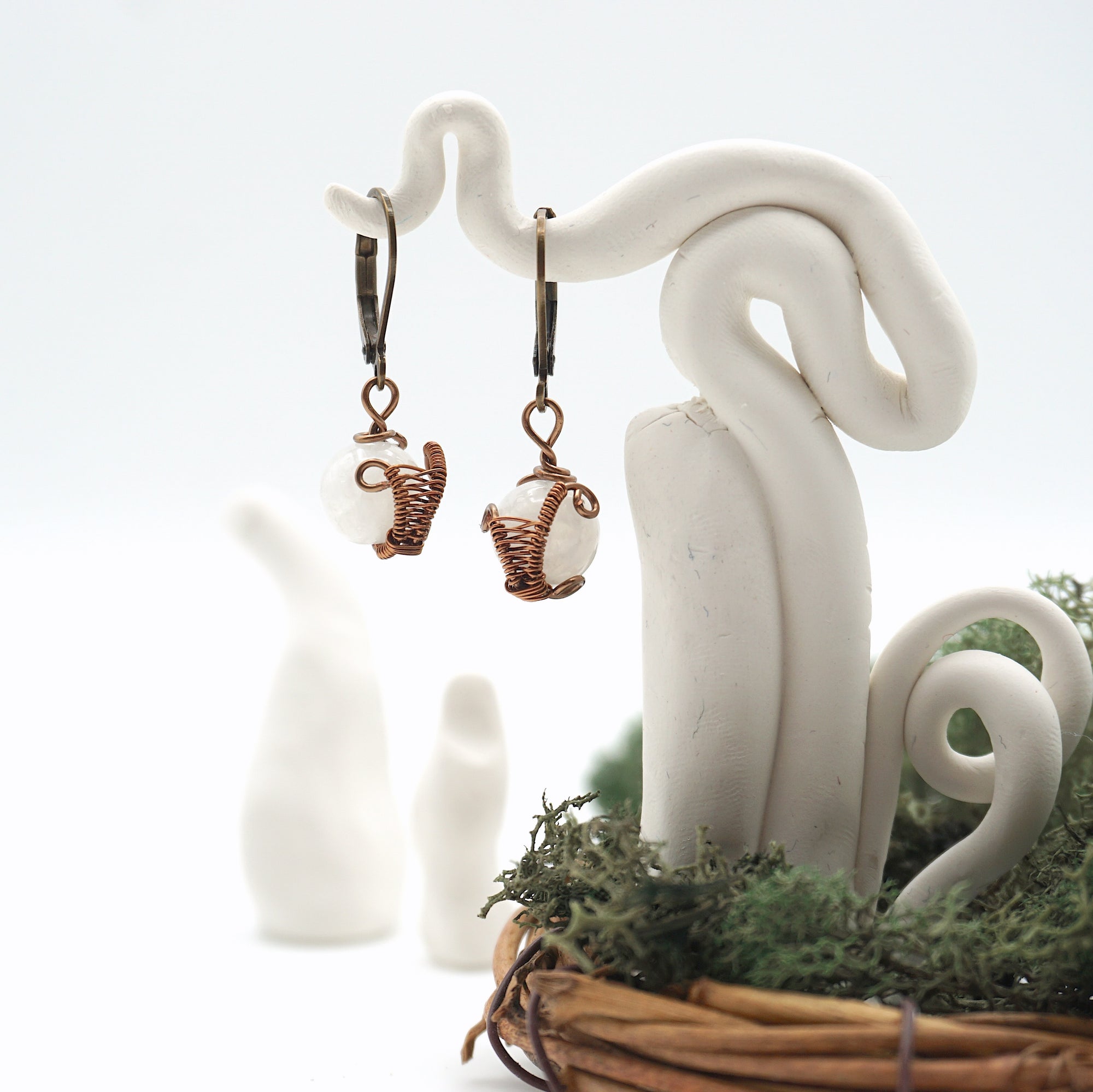 Close-up of handcrafted rainbow moonstone drop earrings with antique bronze copper wire wrapping.