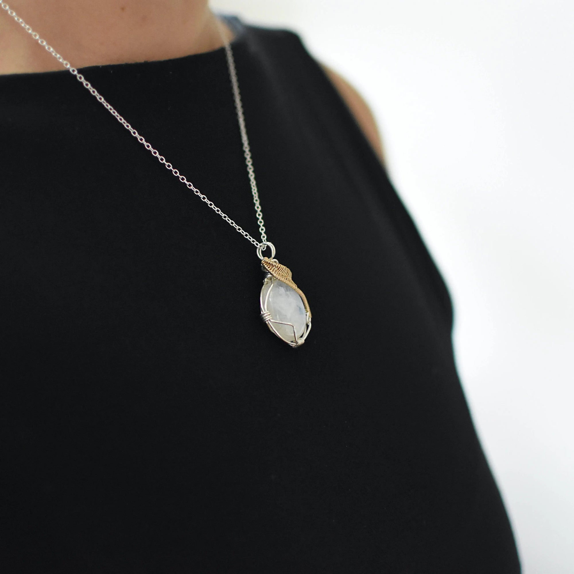 Model wearing rainbow moonstone necklace for women on sterling silver chain, mixed metal wire wrapped pendant (June birthstone).