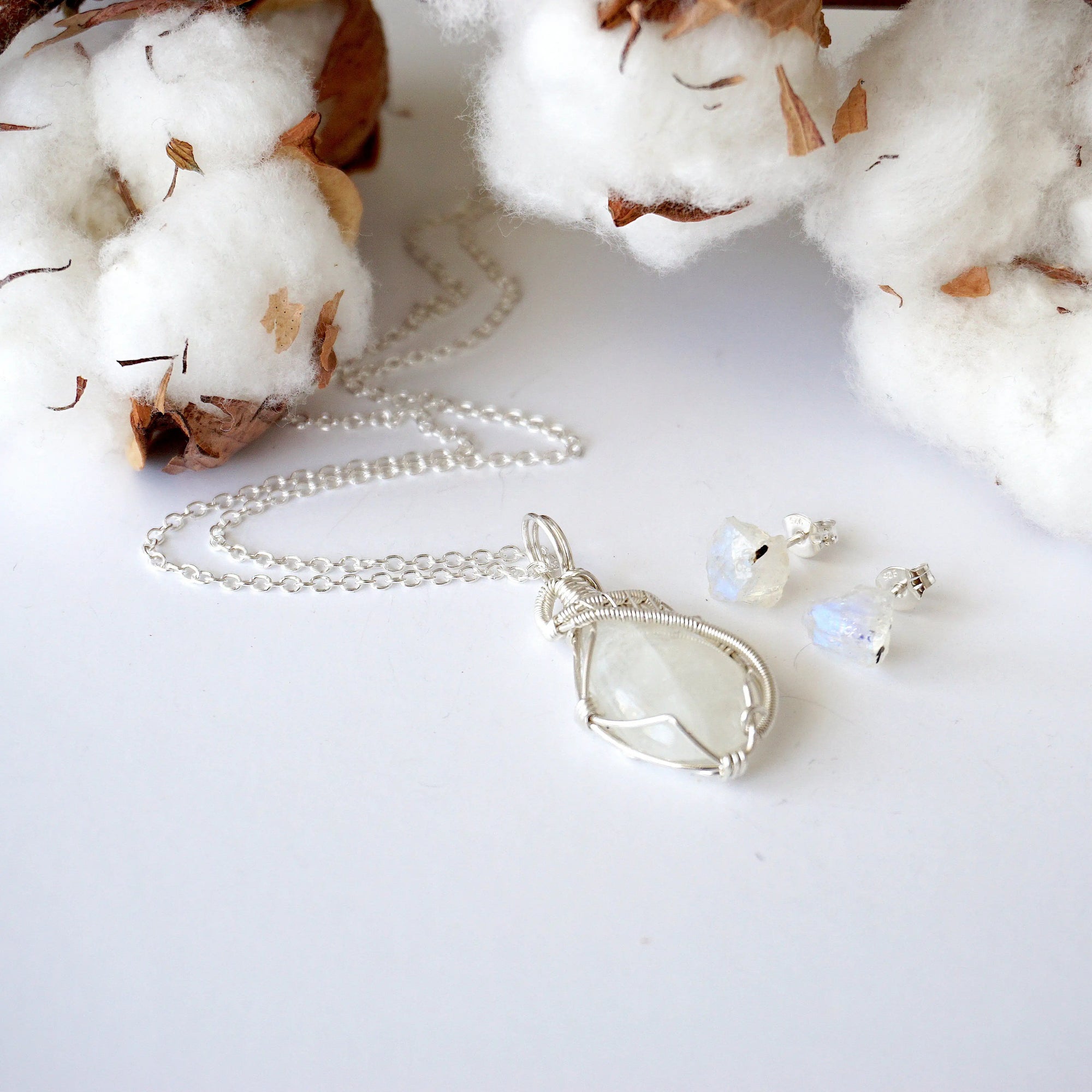 Rainbow moonstone pendant on sterling silver chain with raw rainbow moonstone stud earrings displayed together as a jewelry set.