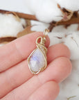 Rainbow moonstone pendant shown in hand for size reference with 14k gold filled artisan wire wrapping for women