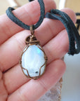 Natural rainbow moonstone pendant shown in hand for size reference with handcrafted antique bronze wire wrapping for men