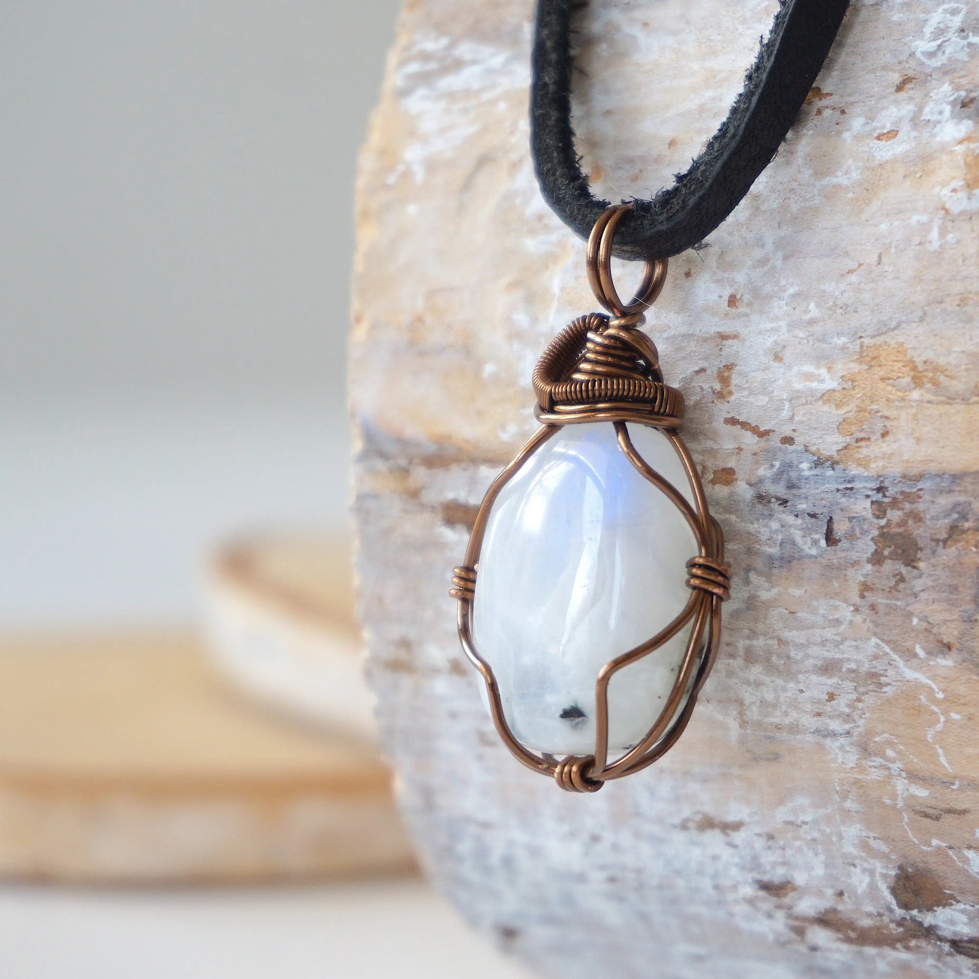 Left angle close-up of natural rainbow moonstone pendant highlighting artisan antique bronze copper wire wrapping