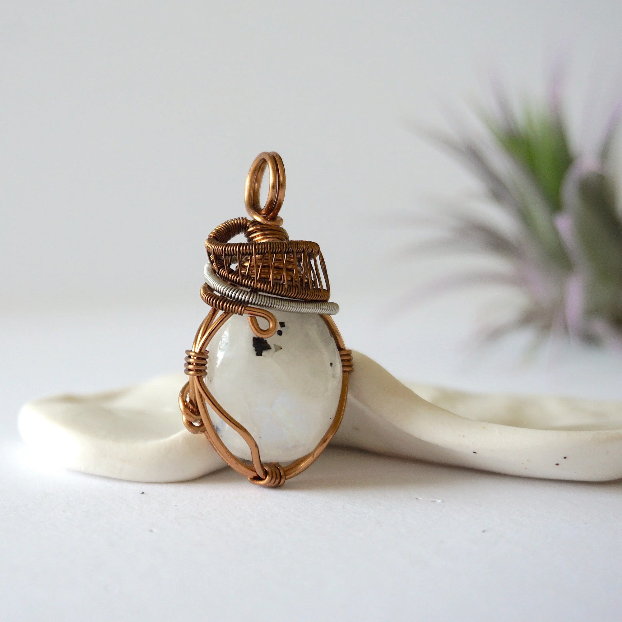Right angle view of rainbow moonstone pendant showing handcrafted mixed metal wire wrapping detail