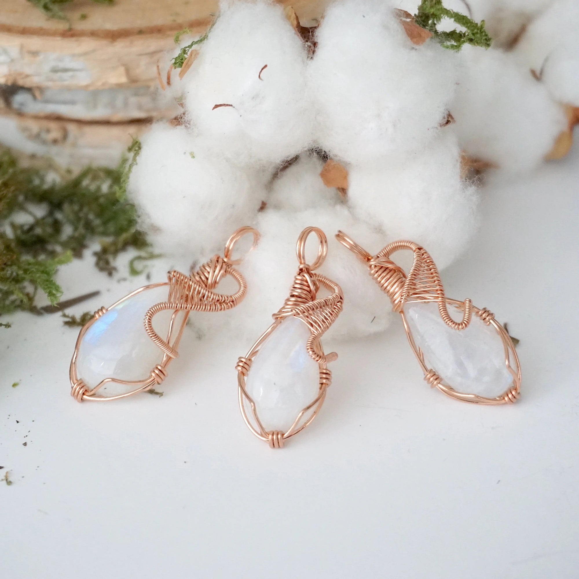 Three rainbow moonstone pendants showing natural variation in size and flash in handmade artisan jewelry