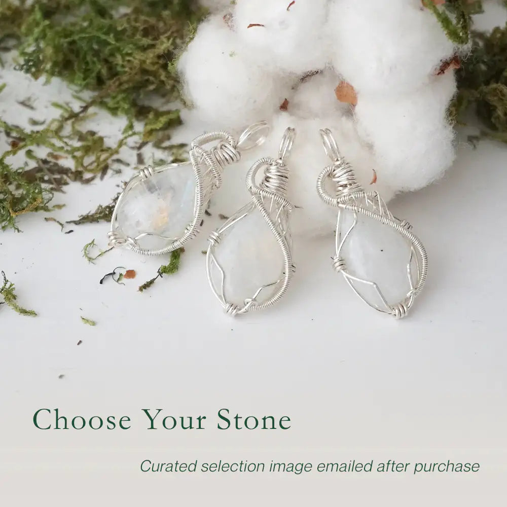 Three rainbow moonstone pendants showing natural variation in size and flash in handmade artisan jewelry