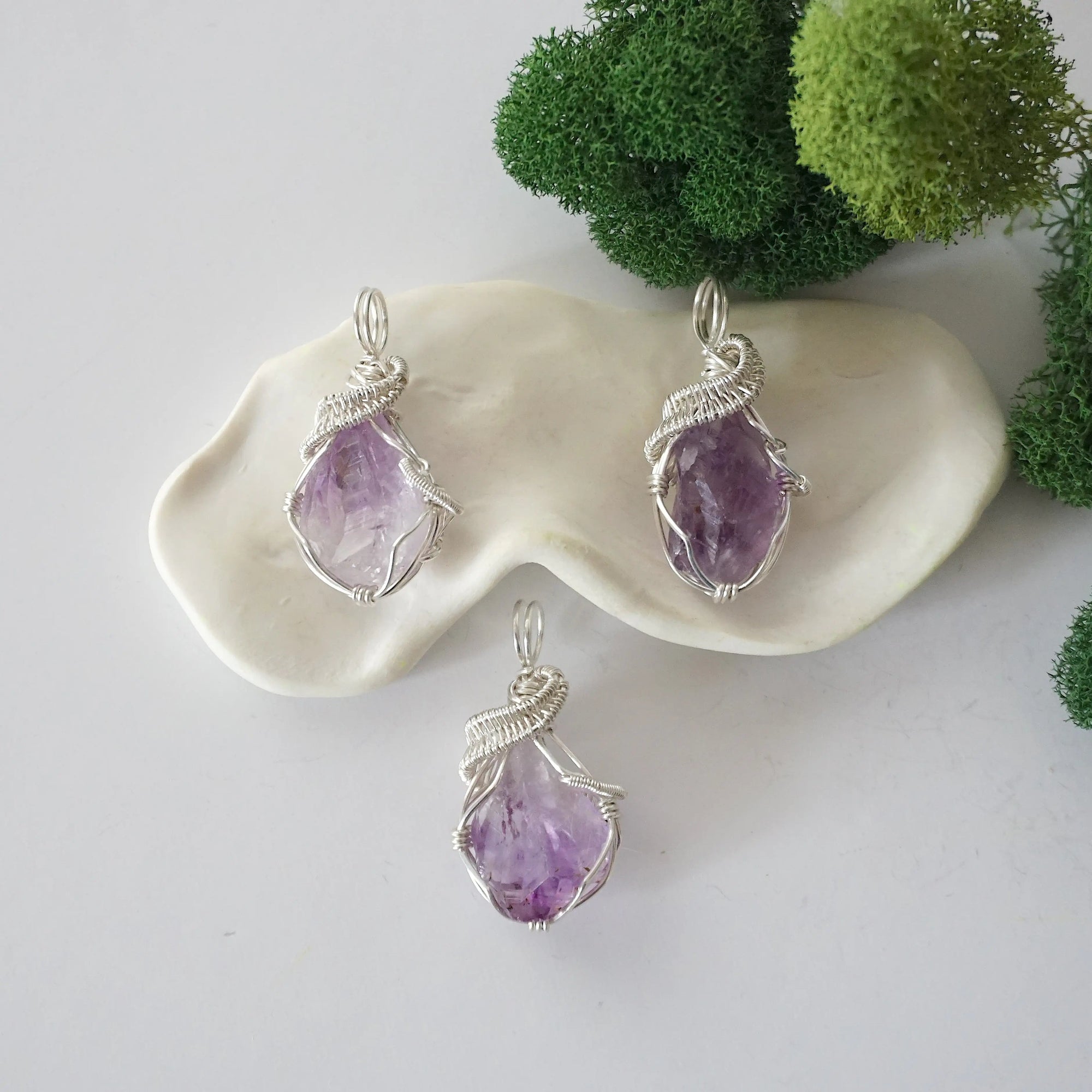 Three raw amethyst necklaces showing natural purple crystal variations in handmade wire wrapped pendants