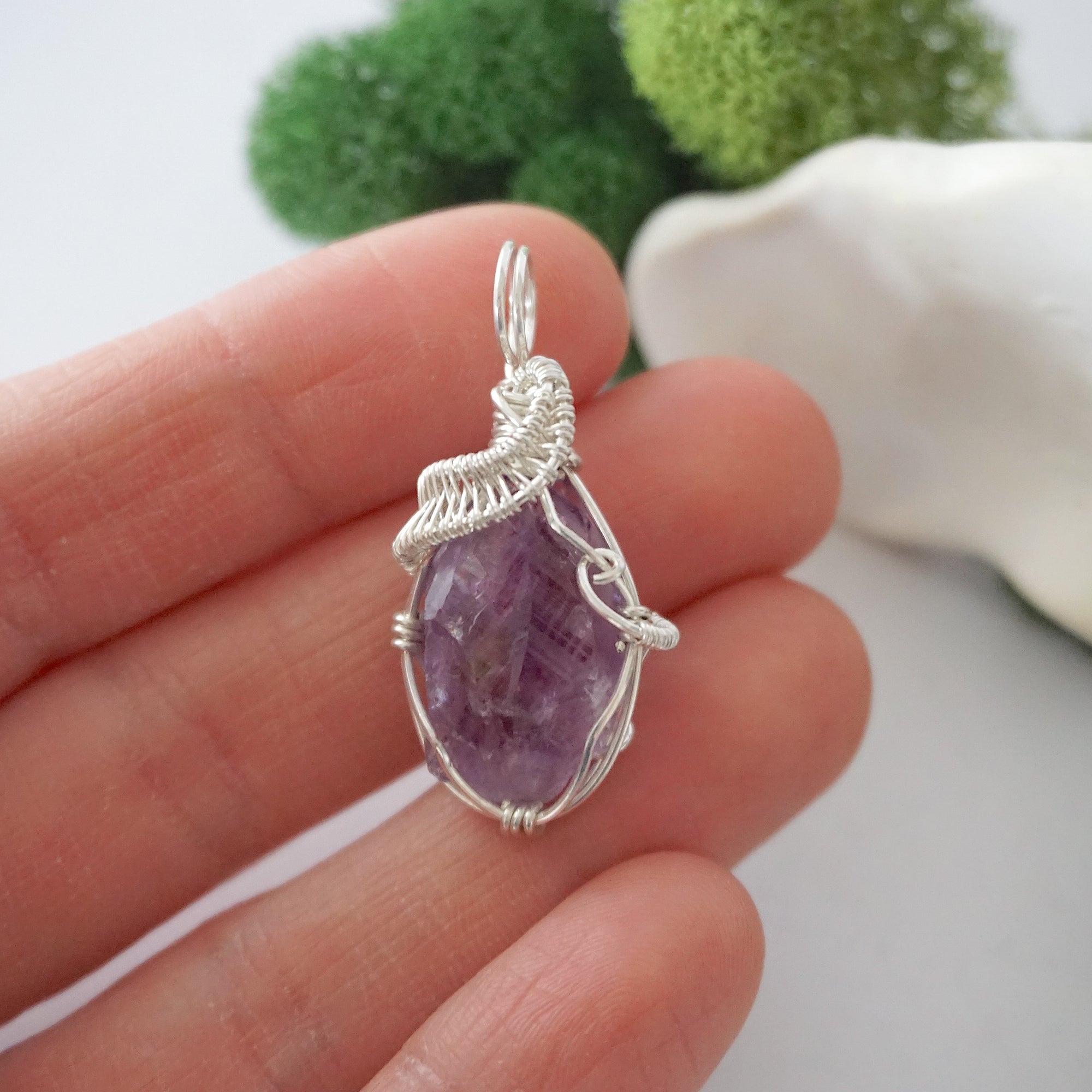 Raw amethyst crystal pendant wire wrapped in sterling silver held in hand showing size