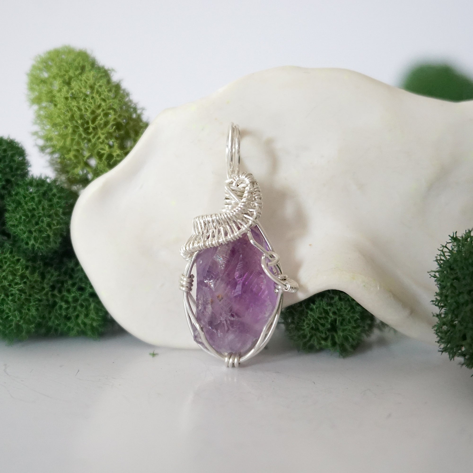 Close up front view of raw amethyst crystal with detailed 925 sterling silver wire wrapping