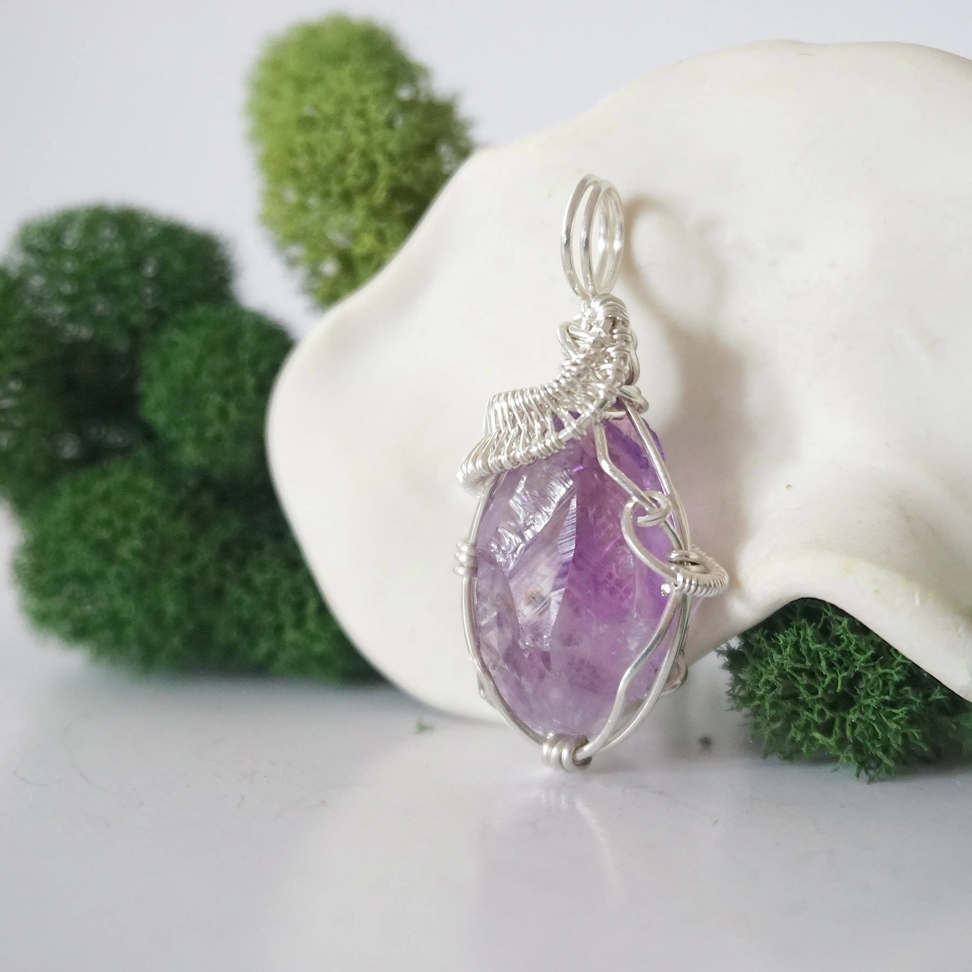 Side angle of raw amethyst pendant showing artisan wire wrapped sterling silver detail