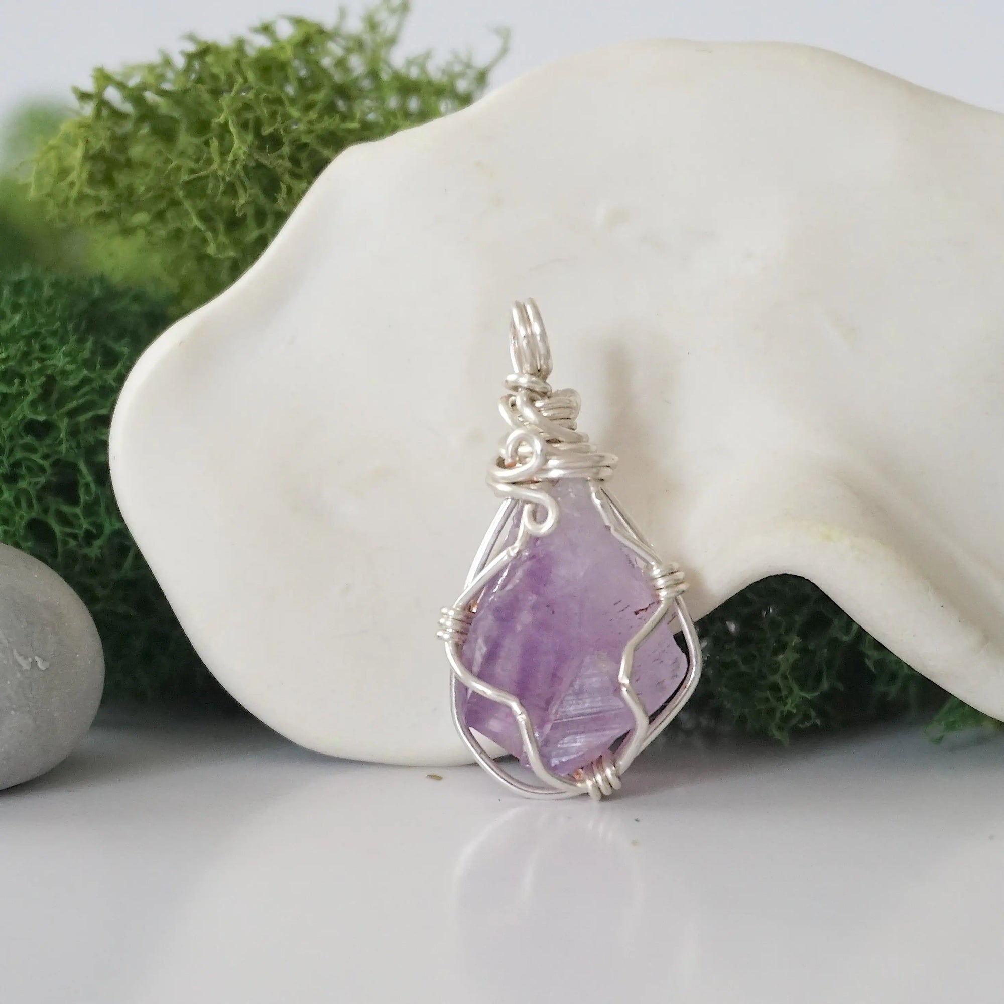 Back angle look at simple raw amethyst pendant with silver wire wrapping