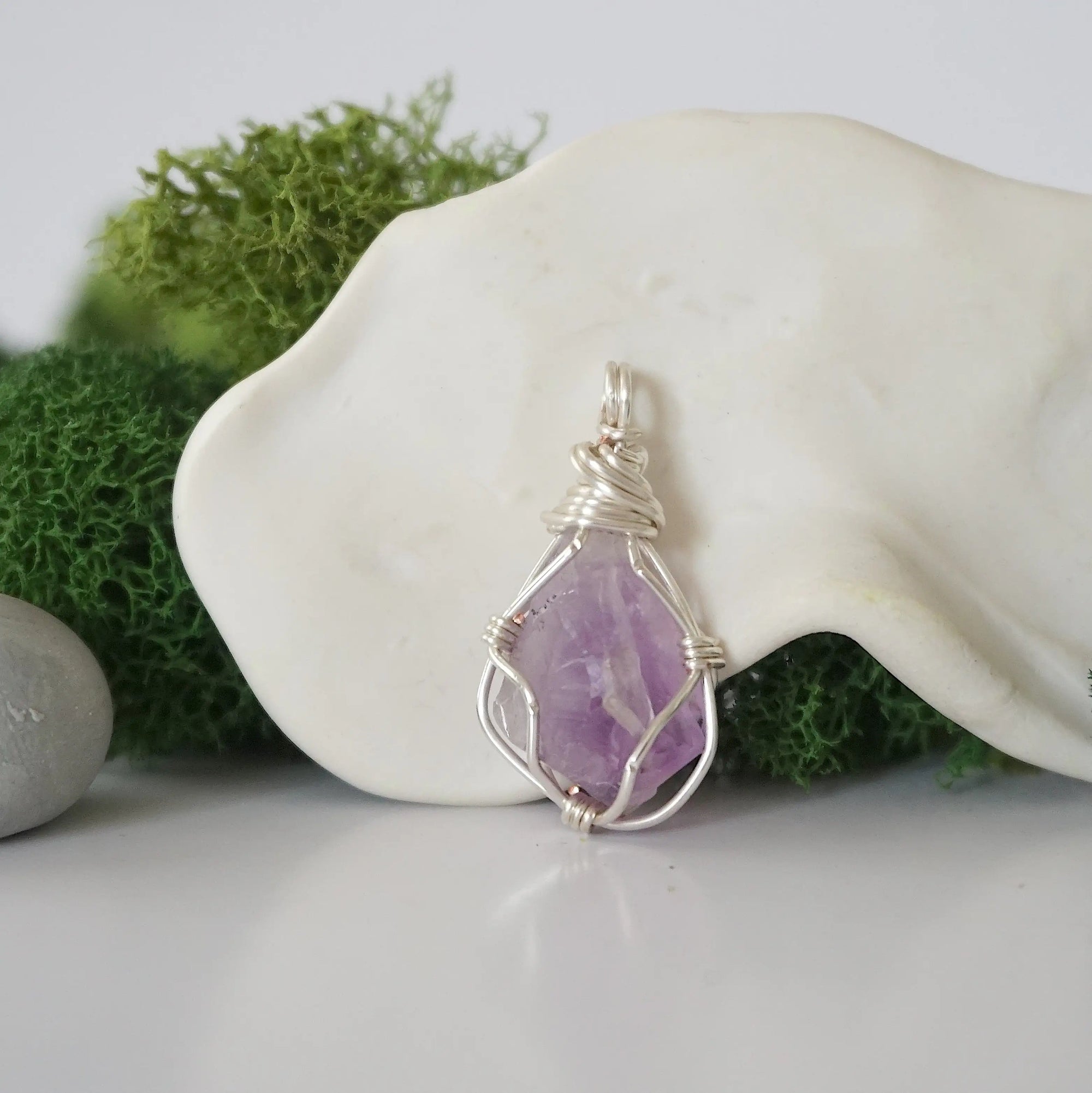 Detailed front angle view of simple raw amethyst pendant in silver wire