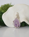 Detailed front angle view of simple raw amethyst pendant in silver wire