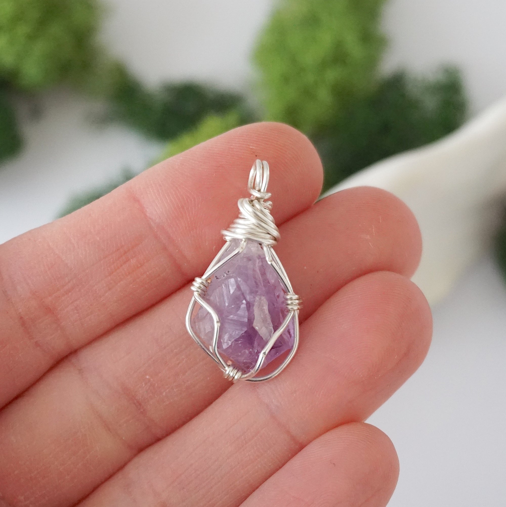Simple raw amethyst pendant shown in hand for size reference