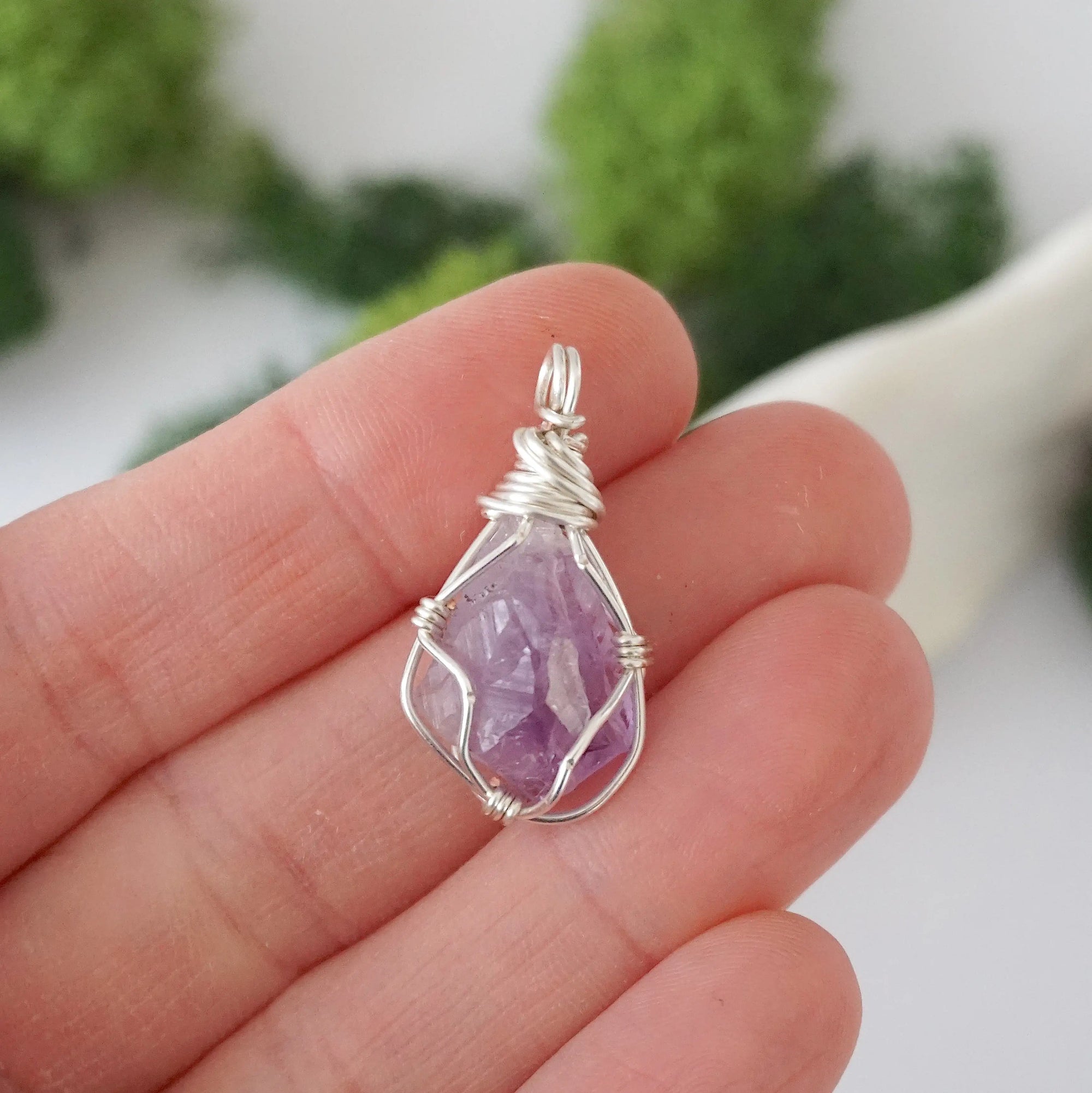 Simple raw amethyst pendant shown in hand for size reference