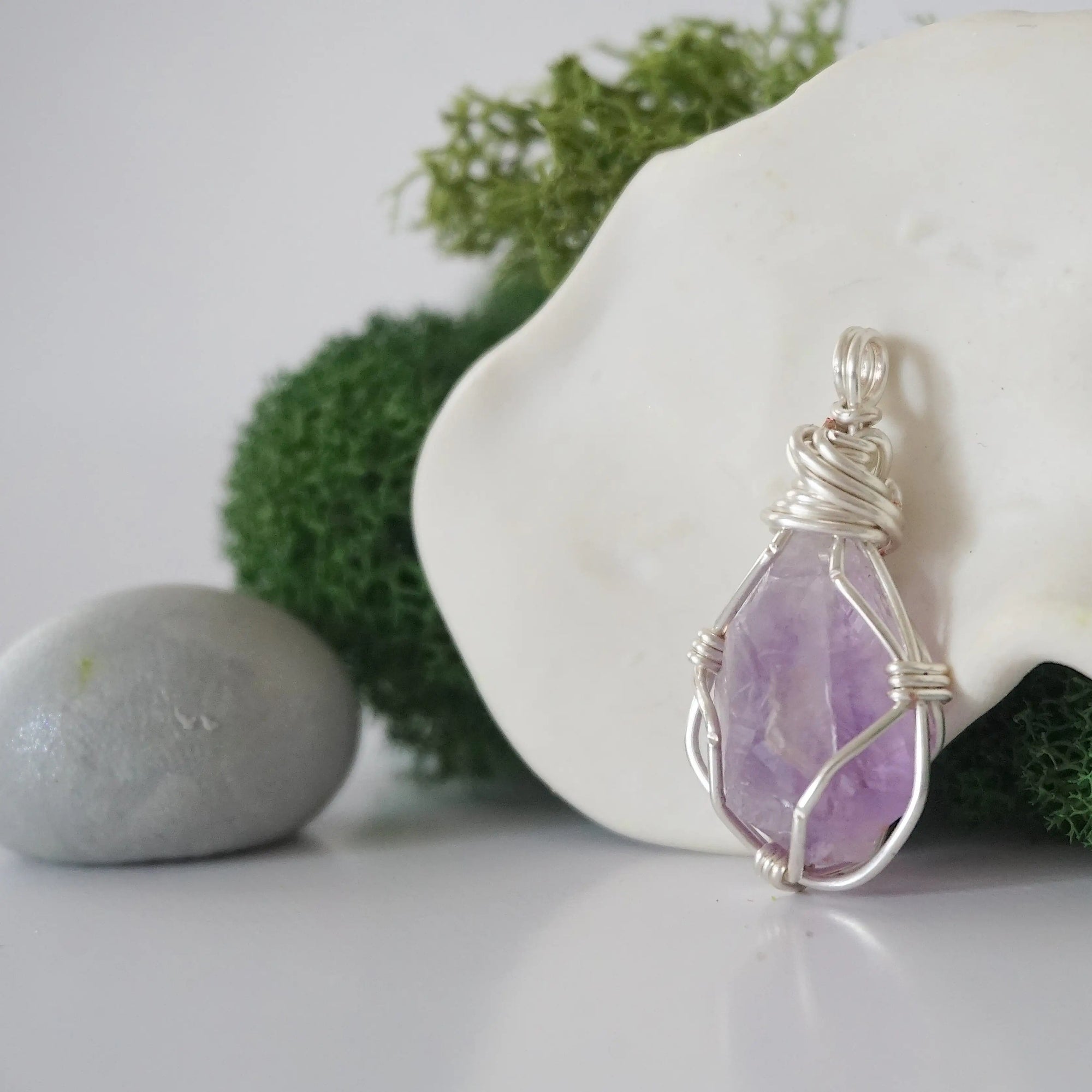 Detailed side angle view of simple raw amethyst pendant in silver wire