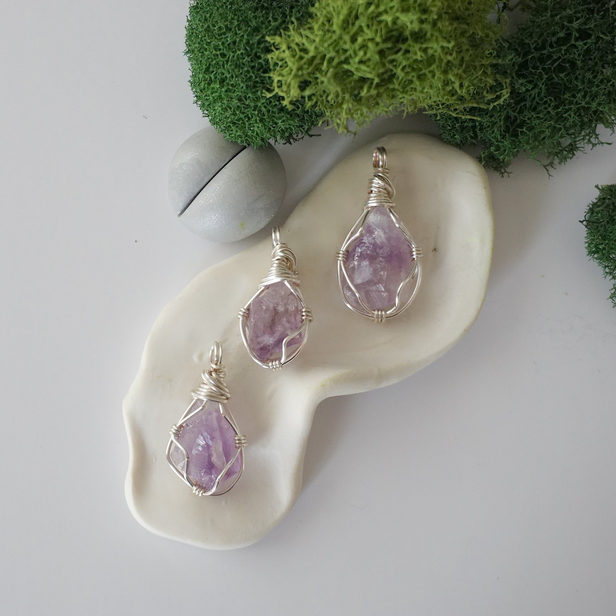 Three different raw amethyst pendants displayed for variation reference