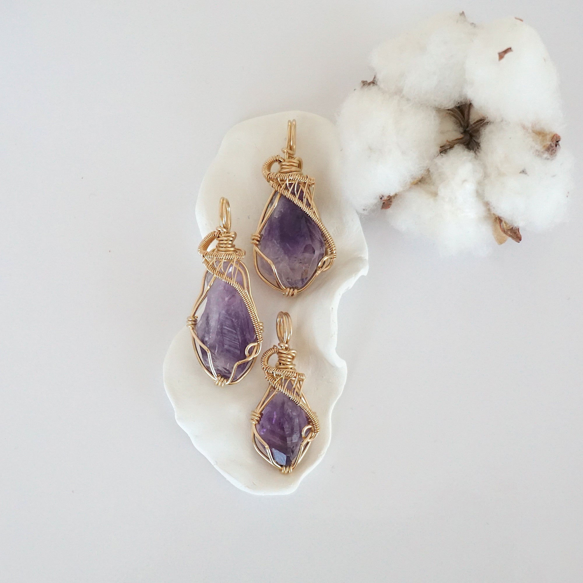 Three raw amethyst pendants in 14k gold filled, showing natural variation in size, shape, and color. Handcrafted February birthstone jewelry by Designs by Nature Gems.