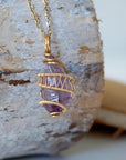 Right side detail of raw amethyst point pendant with intricate gold plated copper wire wrapping on gold plated brass chain