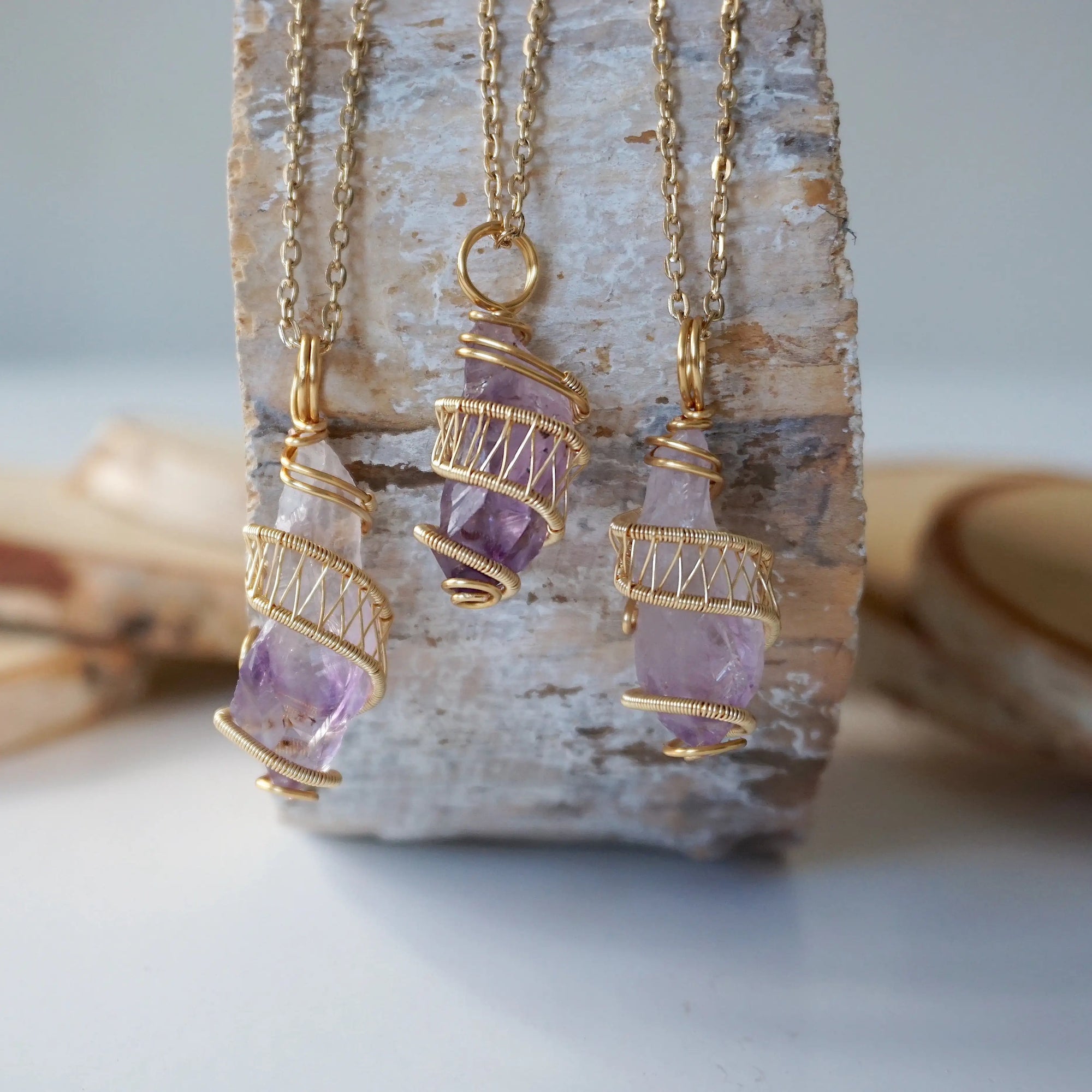 Three raw amethyst point pendant necklaces on gold plated brass chain showing natural variation in crystal color, size, and shape