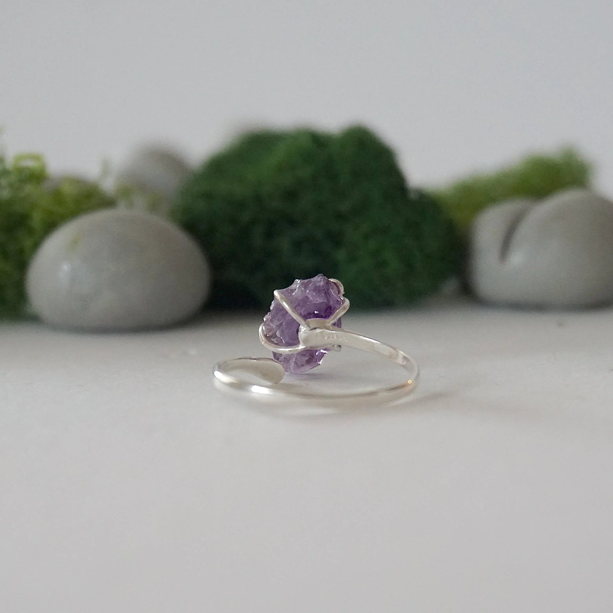 Back view of adjustable sterling silver ring with natural raw amethyst stone in claw setting