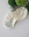 Simple raw aquamarine necklace with silver plated brass chain laying flat