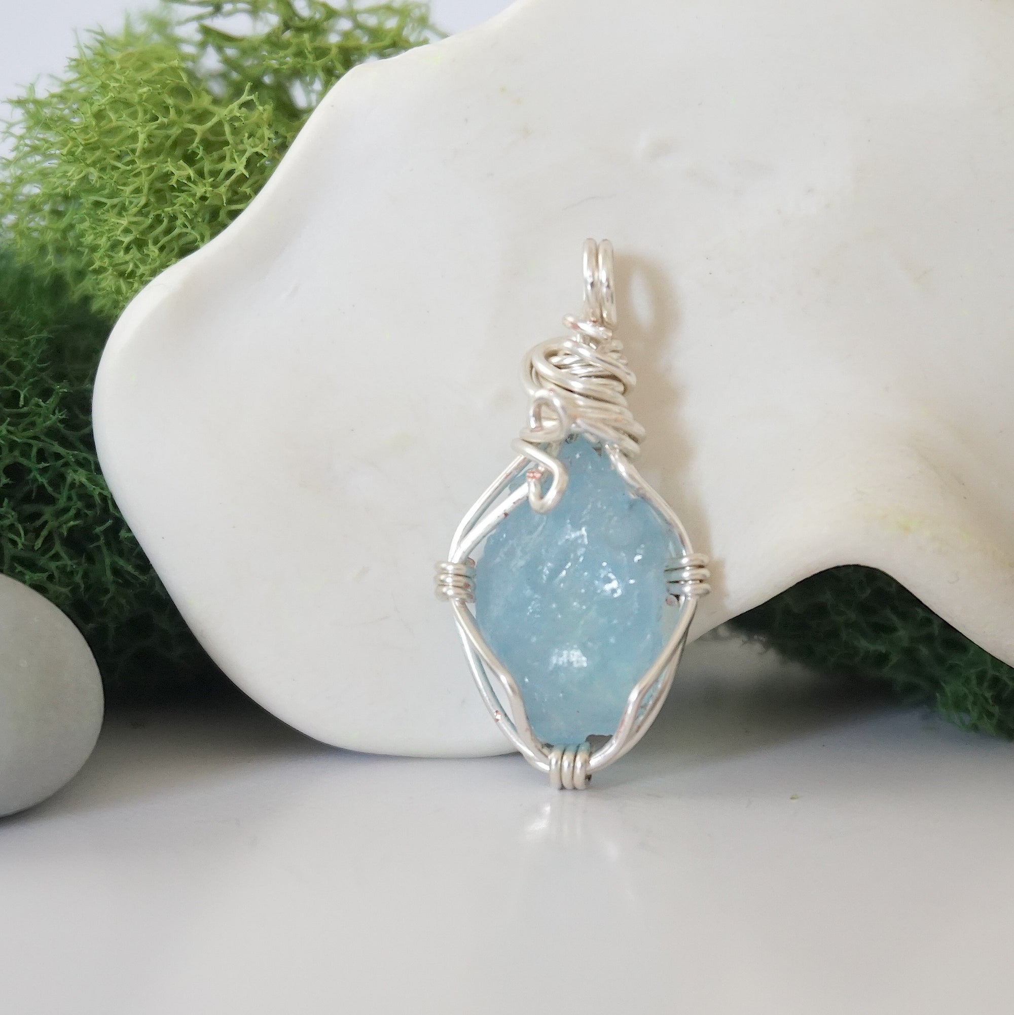 Back angle look at simple raw aquamarine pendant with silver wire wrapping