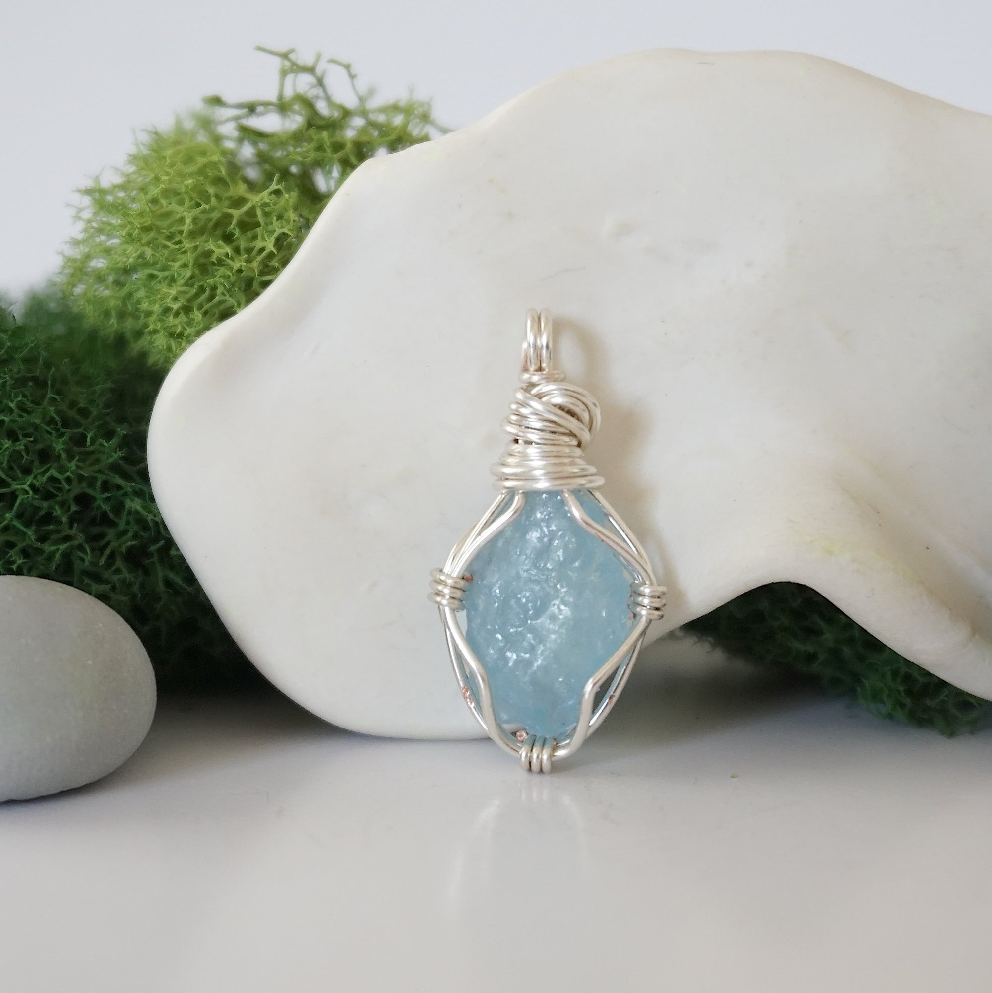 Detailed front angle view of simple raw aquamarine pendant in silver wire