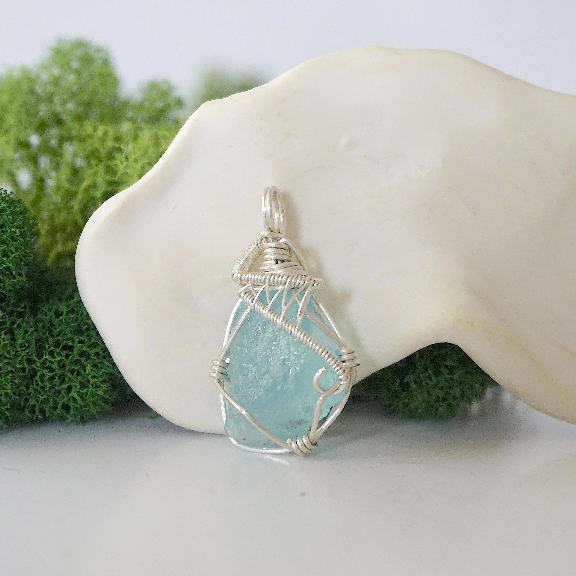 Front view of raw aquamarine pendant — natural unpolished pale blue aquamarine stone hand-wrapped in detailed 925 sterling silver wire, handcrafted artisan jewelry