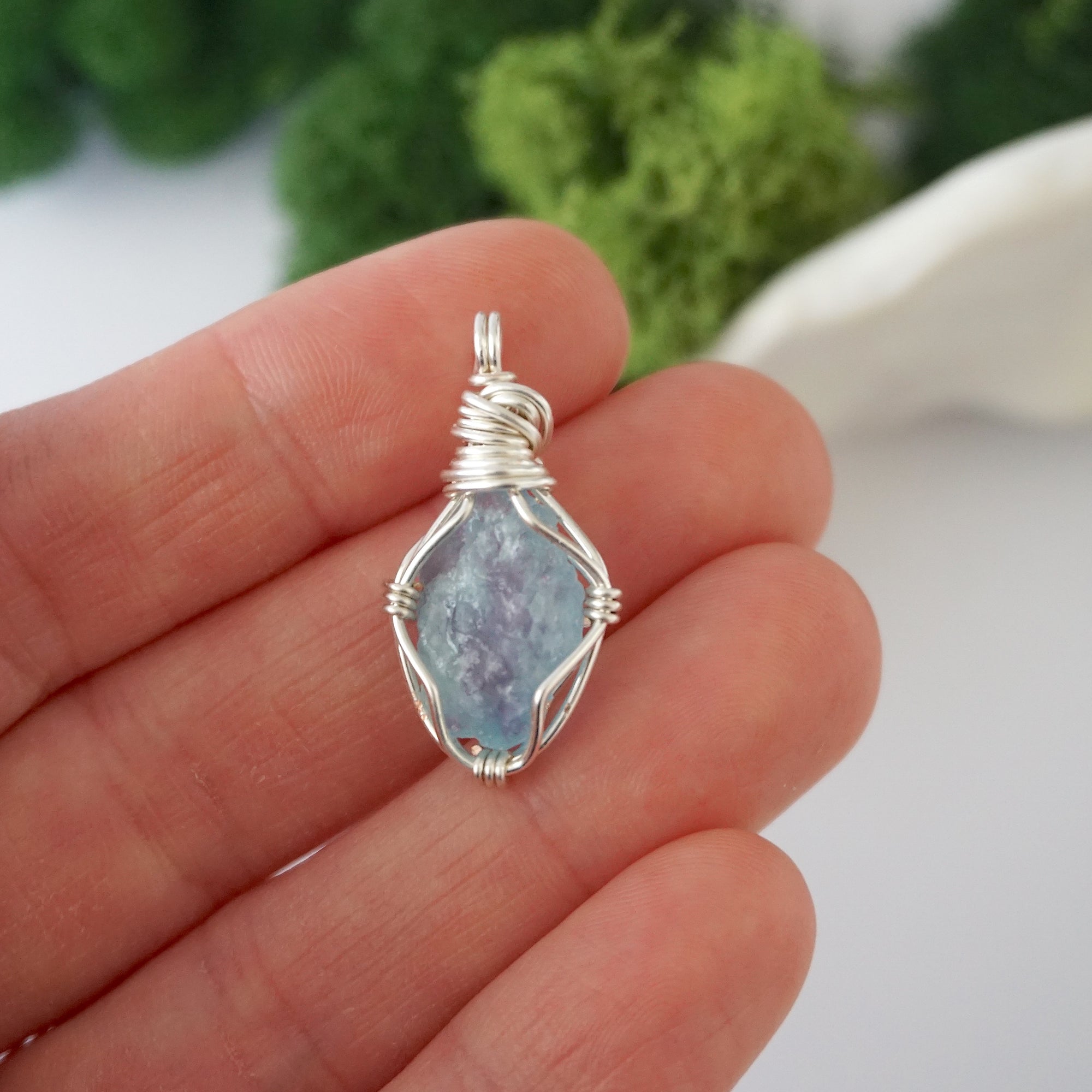 Simple raw aquamarine pendant shown in hand for size reference