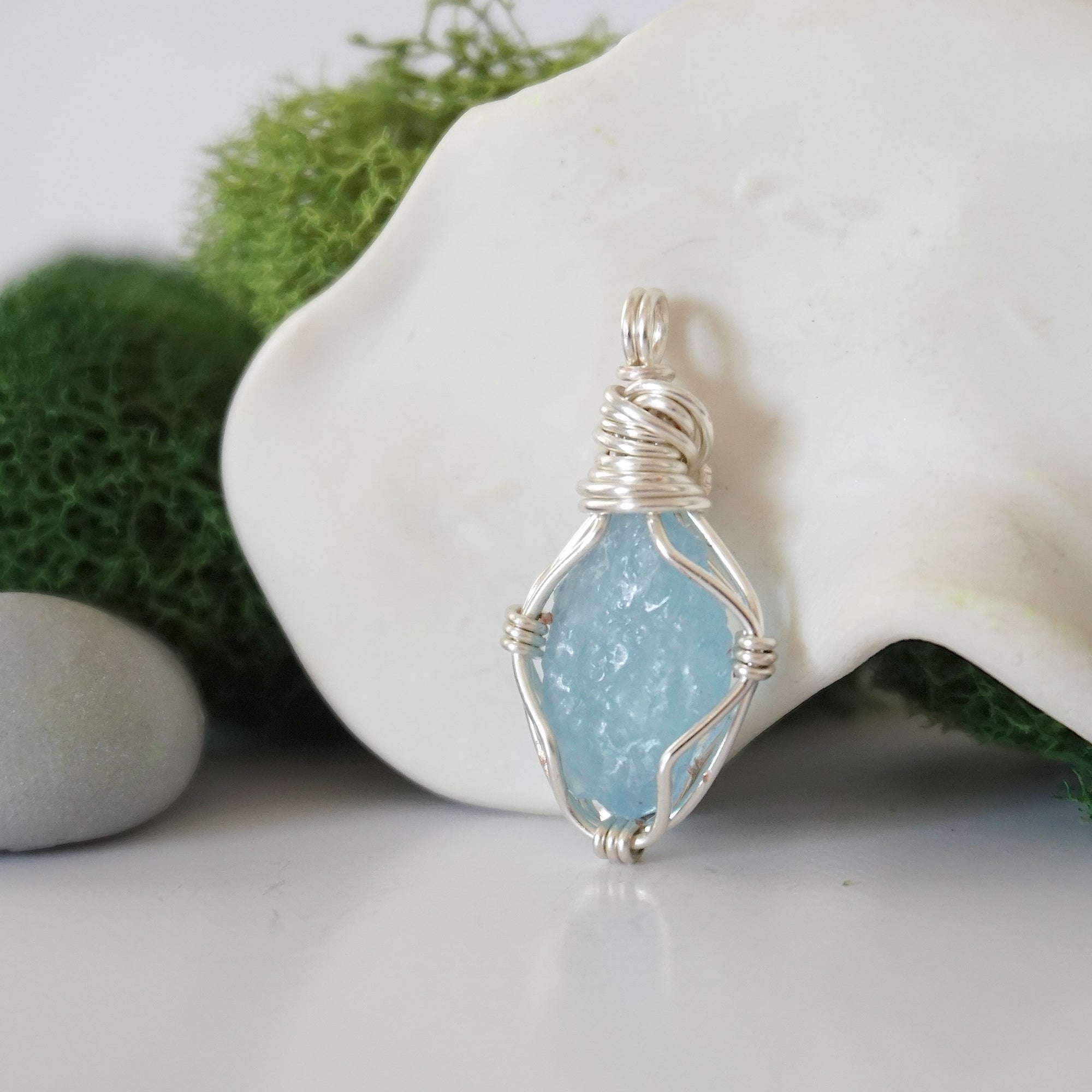 Detailed side angle view of simple raw aquamarine pendant in silver wire