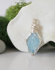 Detailed side angle view of simple raw aquamarine pendant in silver wire