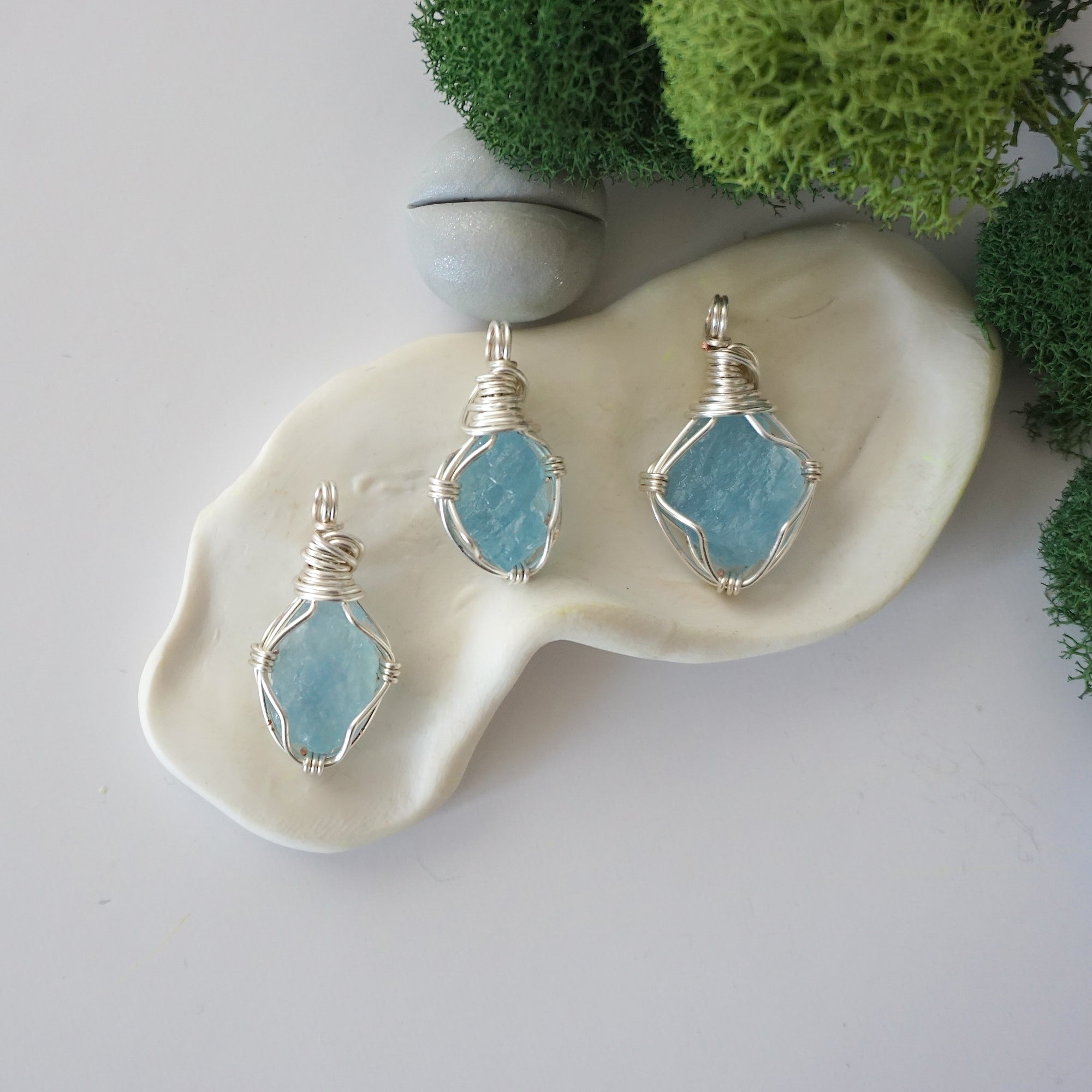 Three different raw aquamarine pendants displayed for variation reference