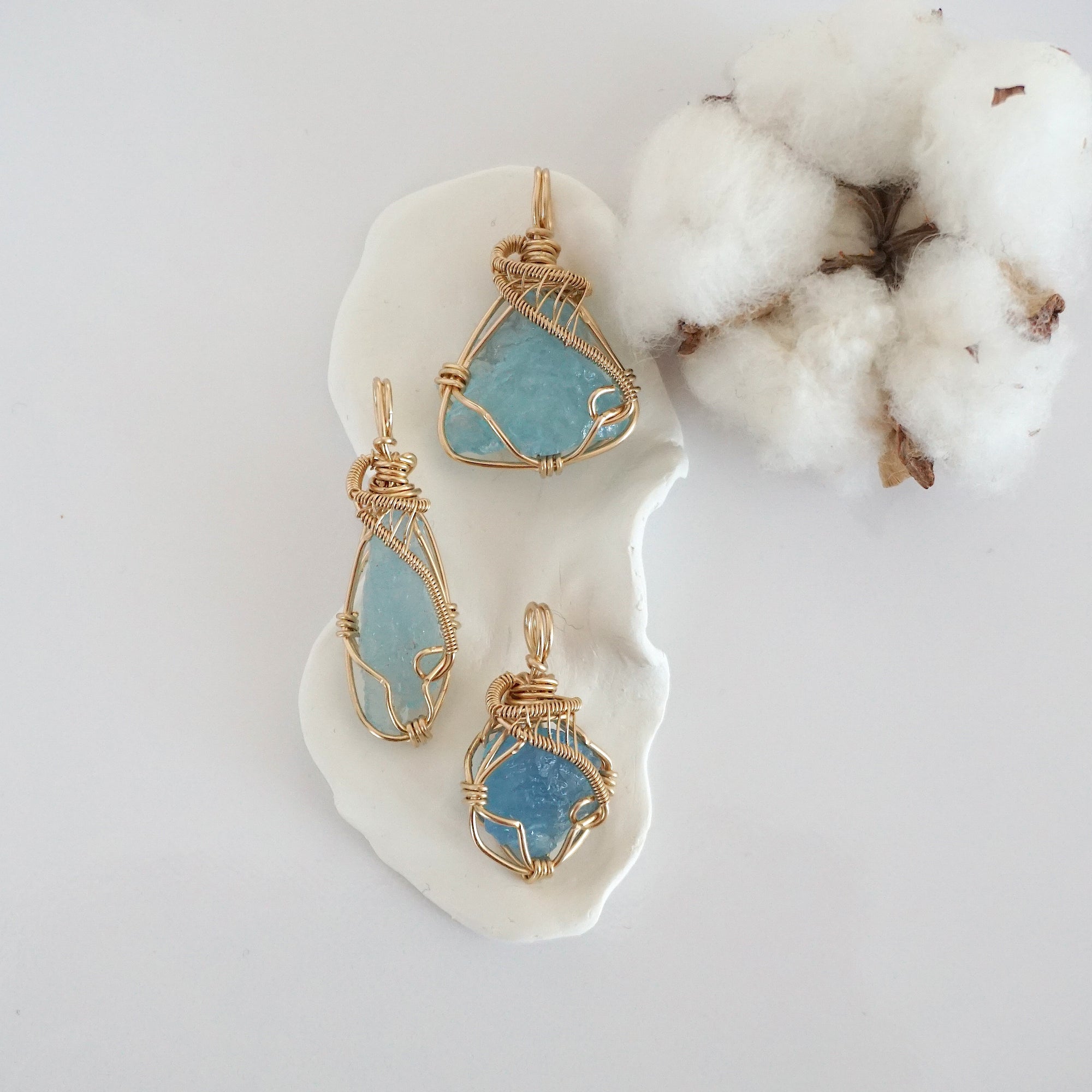 Three raw aquamarine pendants in 14k gold filled, showing natural variation in size, shape, and color. Handcrafted March birthstone jewelry by Designs by Nature Gems.