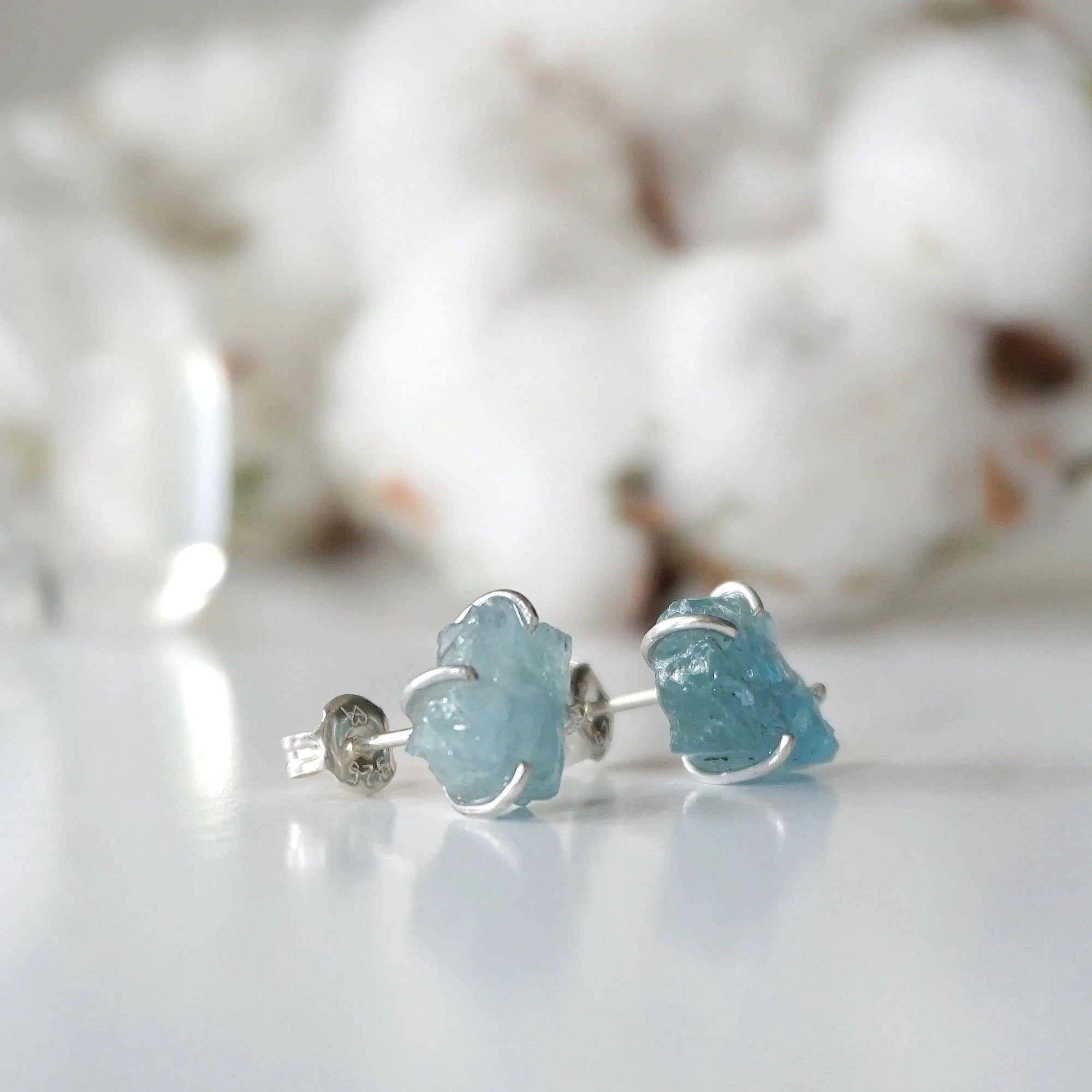 Right side angle of raw aquamarine stud earrings, minimalist sterling silver claw setting, March birthstone