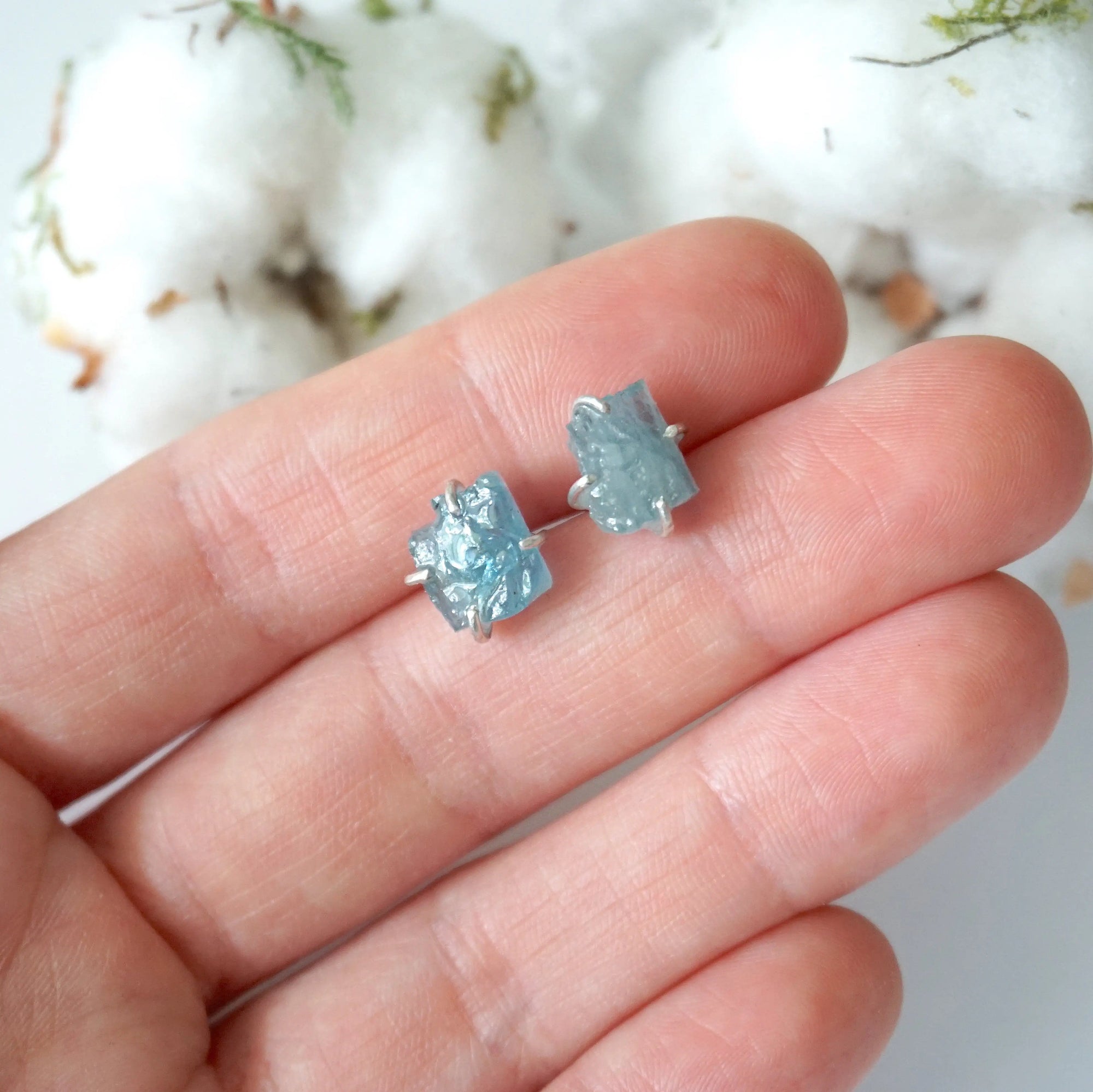 Raw aquamarine stud earrings shown in hand for size reference. Artisan March birthstone earrings by Designs by Nature Gems
