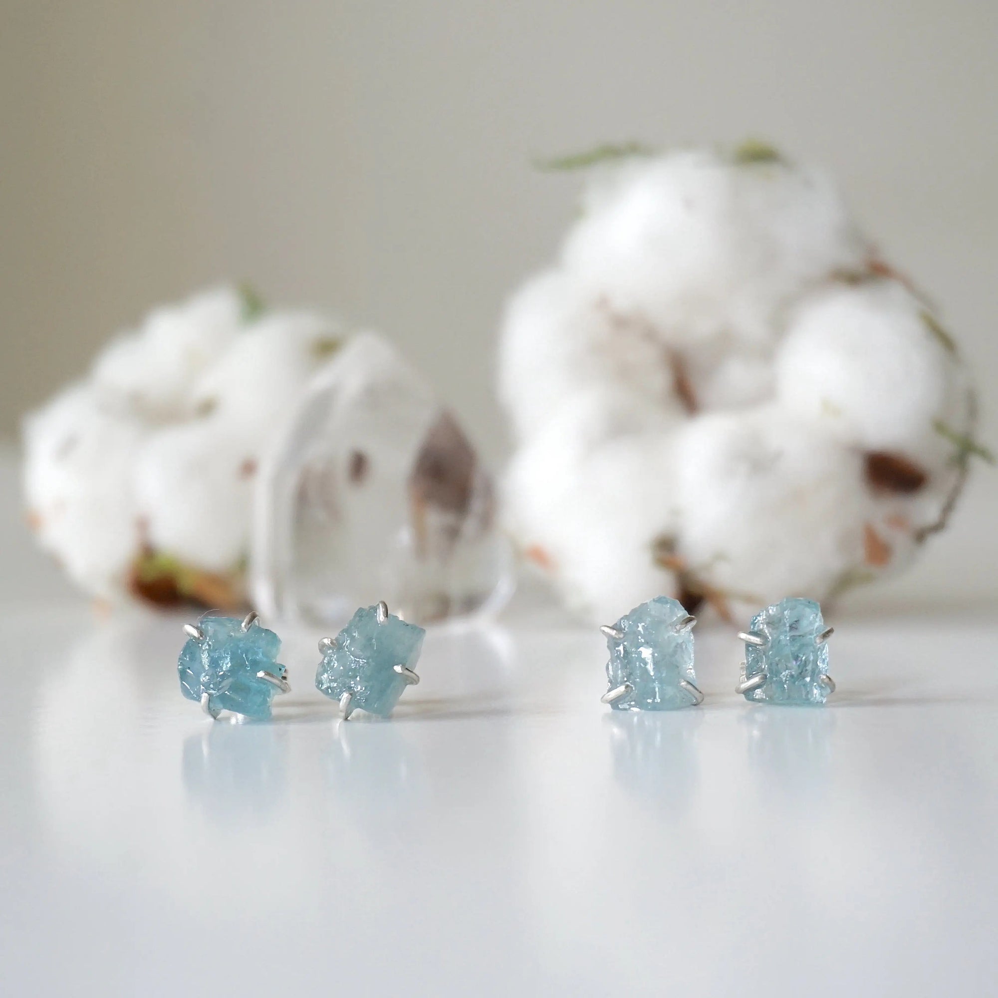 Two pairs of raw aquamarine stud earrings showing natural variation in size, shape, and blue color, Designs by Nature Gems